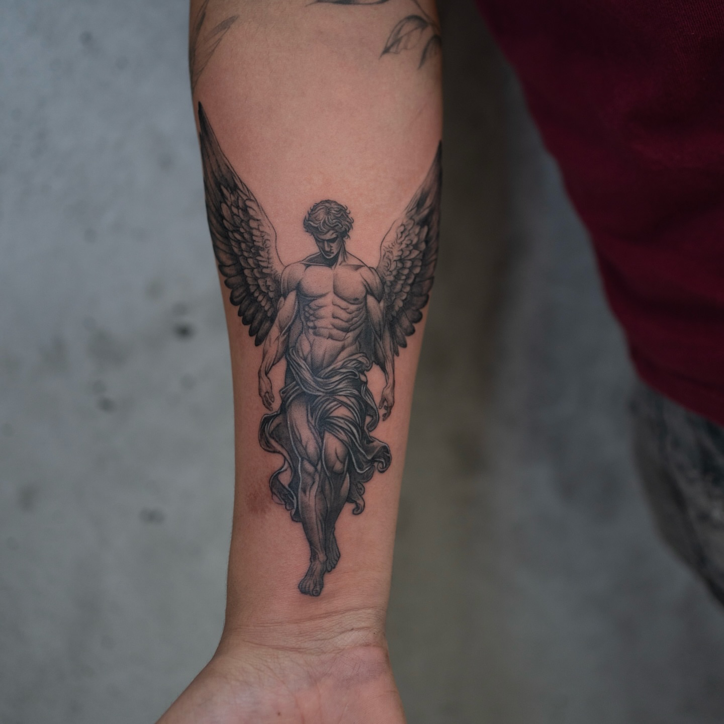 Statue of an angel black and grey tattoo on the forearm by Damon Valdez