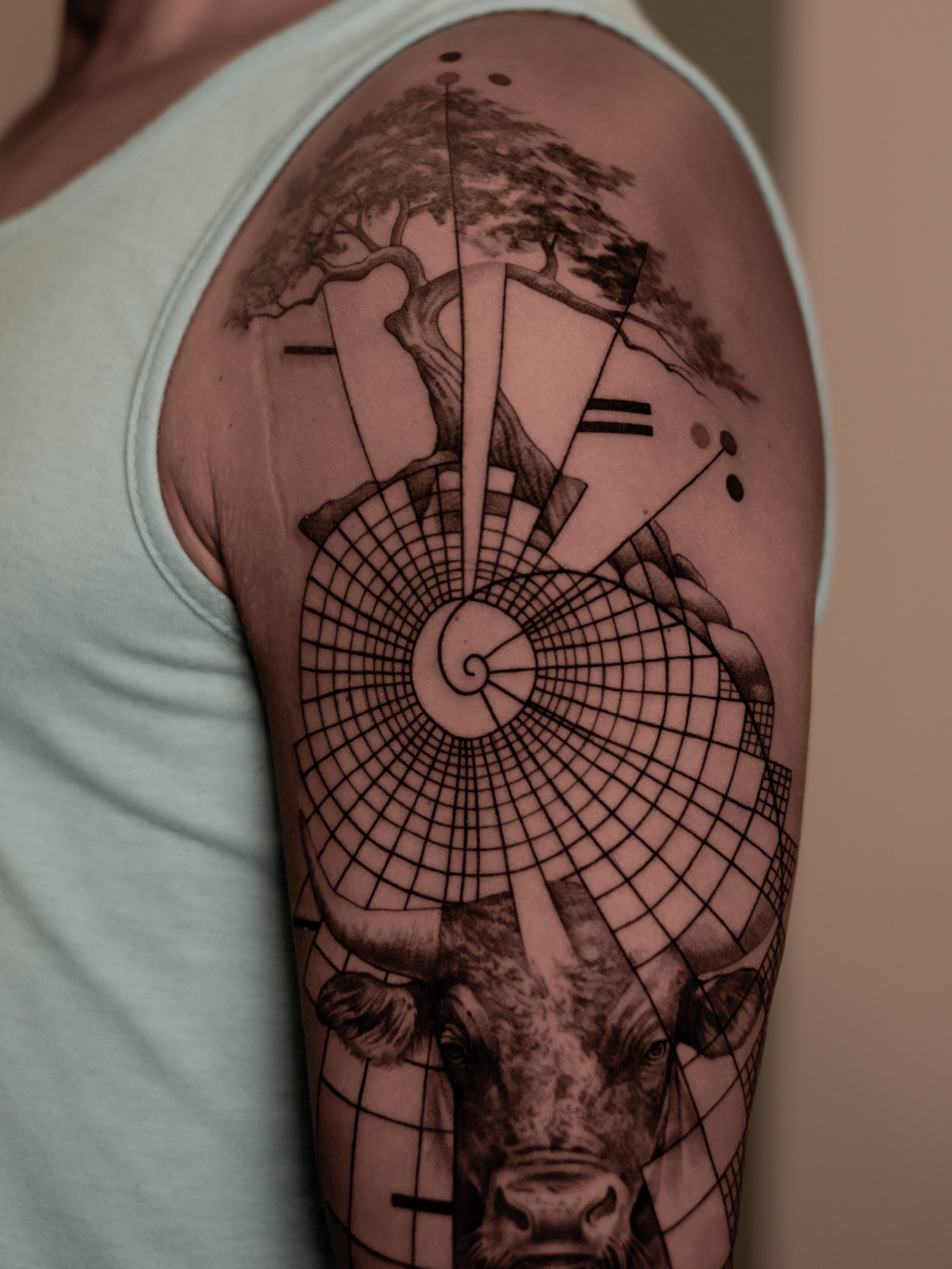 Bull and geometric design geometric tattoo on the upper arm by Mark D, Los Angeles, California