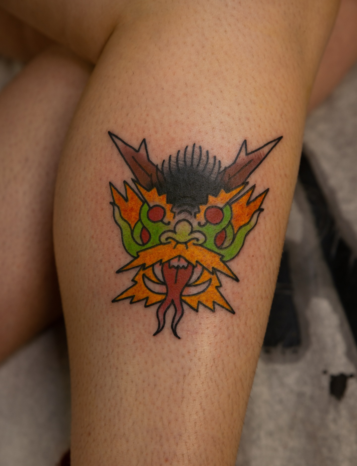 Dragon mask American traditional tattoo on the thigh by Trevor Aarsvold, Minneapolis, Minnesota