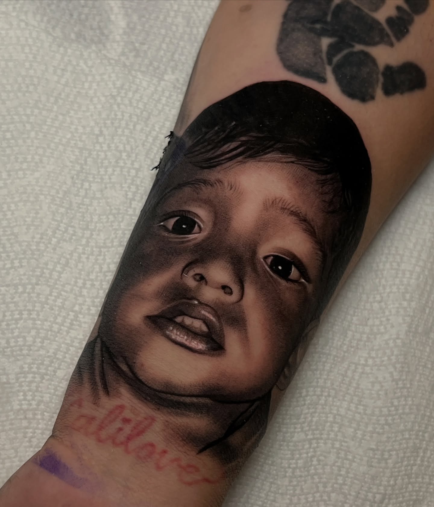 Baby portrait realism tattoo on the forearm by Flames, Cerritos, California