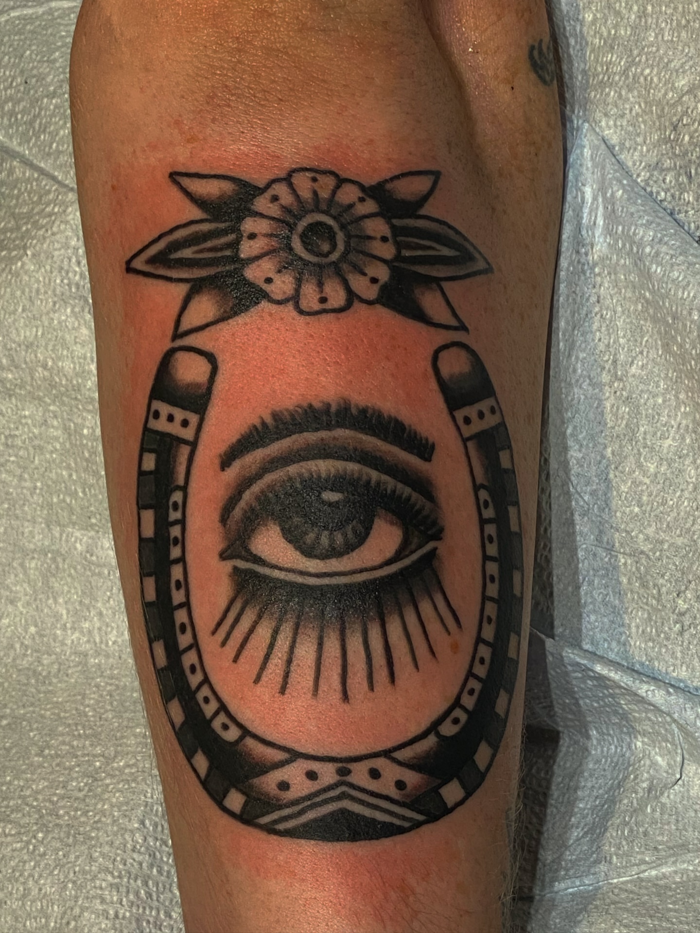 Eye with horseshoe and flower American traditional tattoo on the forearm by Joey Delarosa, San Francisco, California