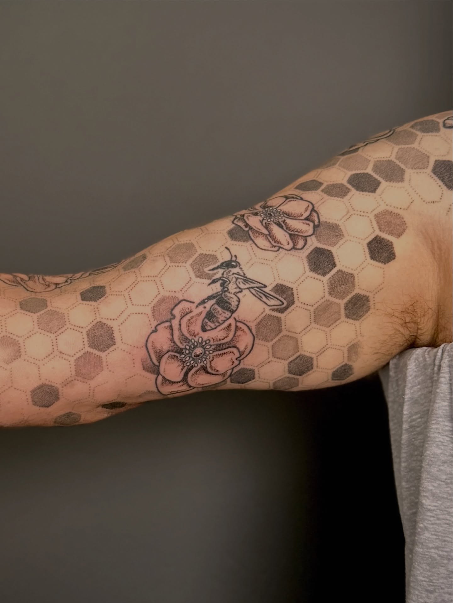 Flower and bee black and grey tattoo on the forearm by Maddie Morrill