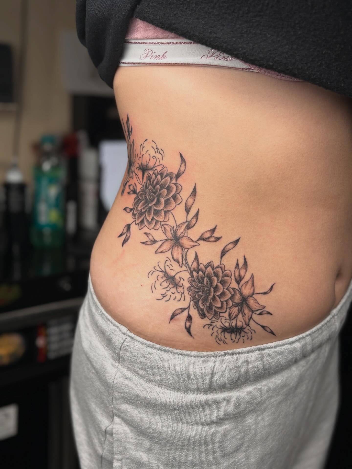 Floral arrangement black and grey tattoo on the ribs by Tessa Simmons - Tattoo Artist