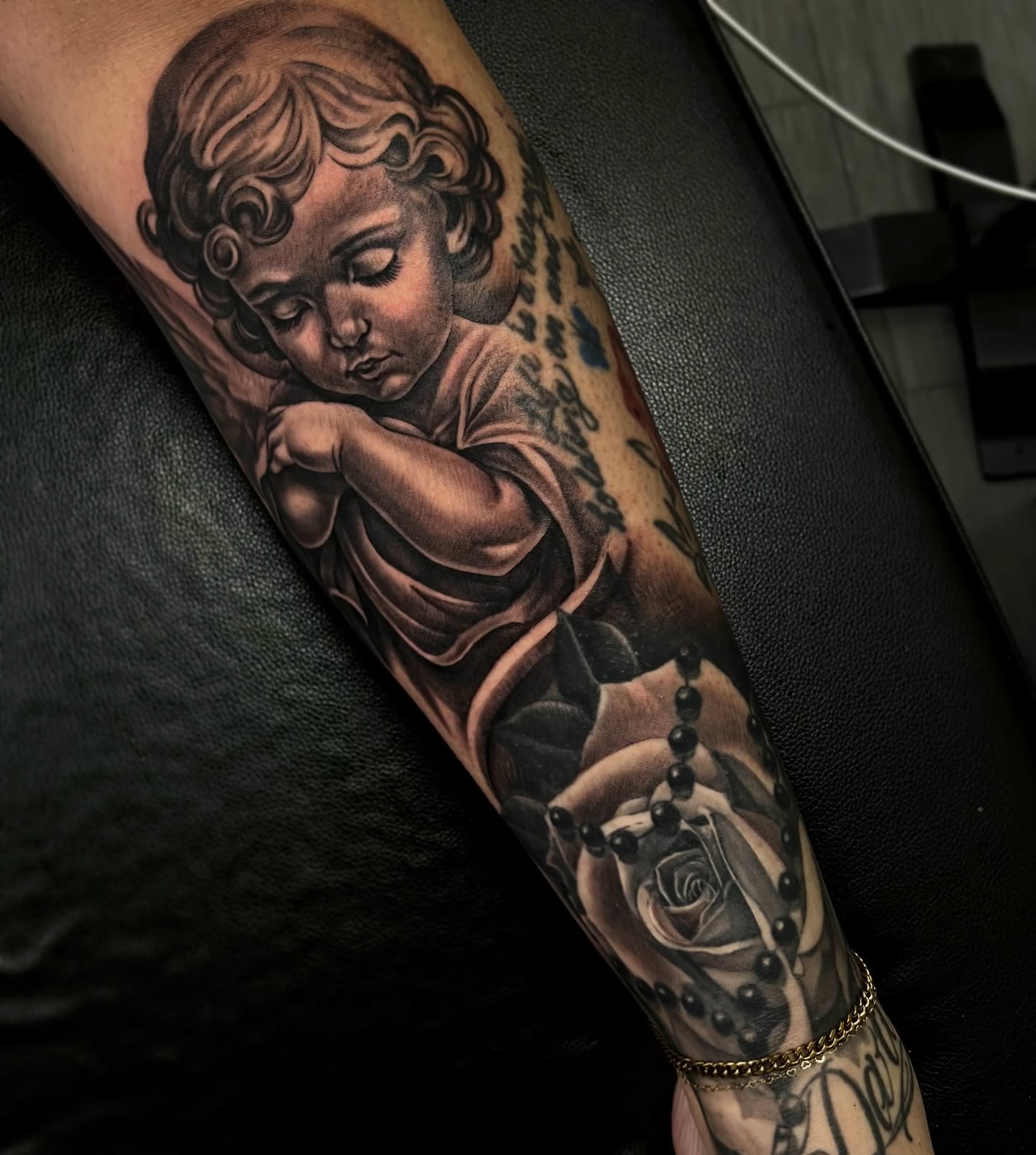 Cherub with rosary realism tattoo on the forearm by Vondrae