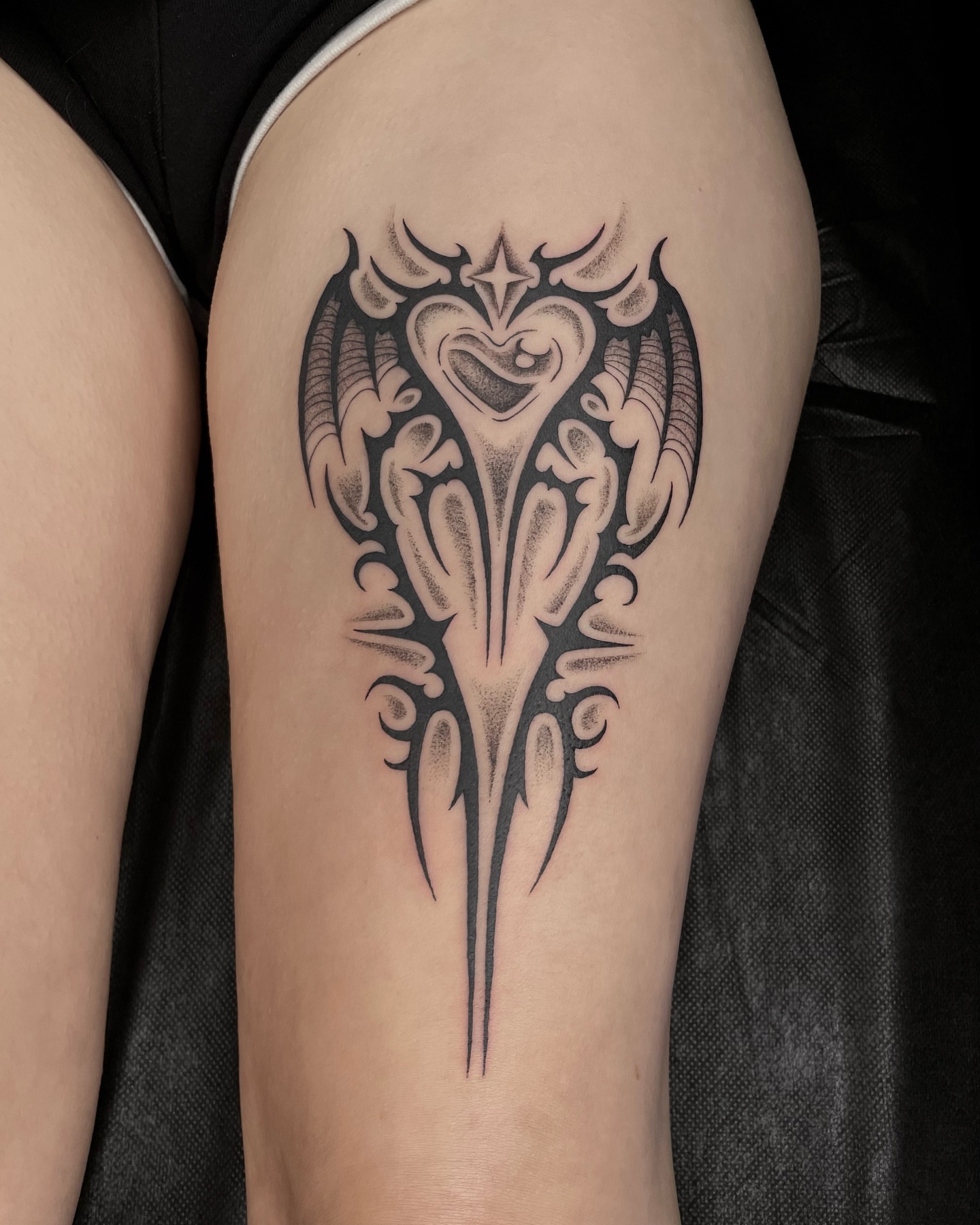 Heart with wings tribal tattoo on the thigh by Tattoo Artist, in San Francisco, CA