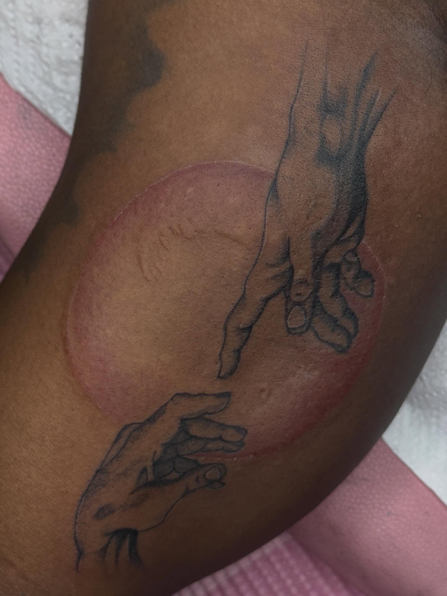 Hands reaching towards each other black and grey tattoo on the upper arm by Destini