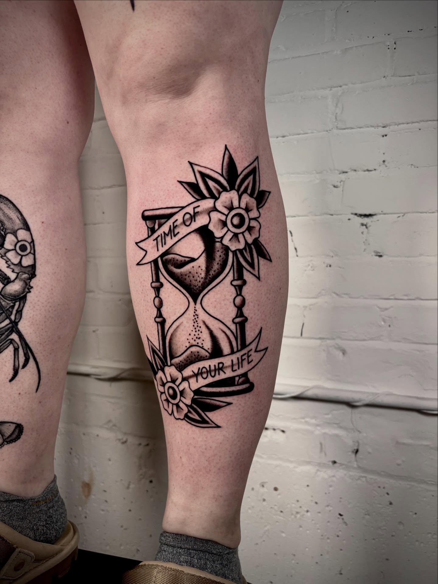 Hourglass and flowers American traditional tattoo on the calf by Doug von