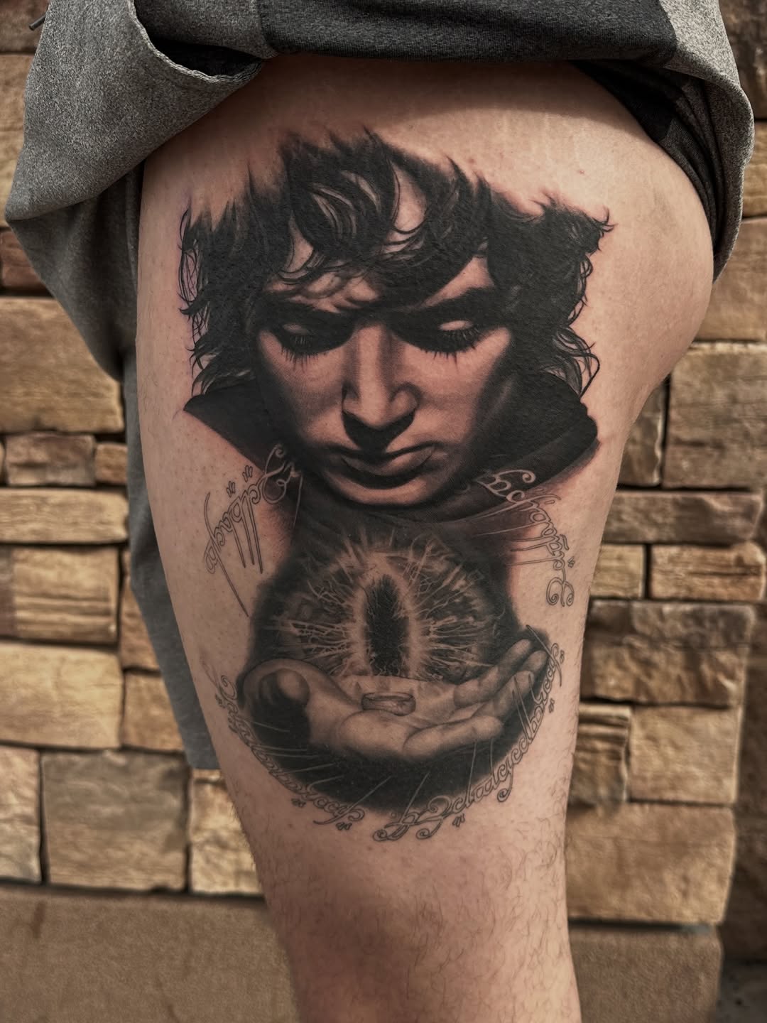 Frodo Baggins holding the One Ring surrealism tattoo on the thigh by Winters Ashurst - St. George tattoo artist