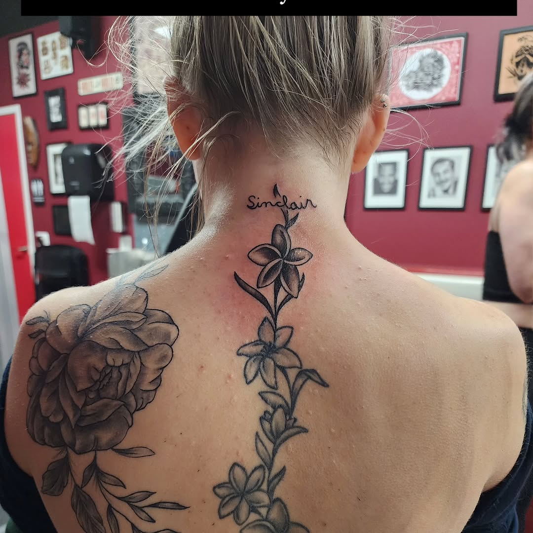 Script lettering and flowers fine line tattoo on the back by @thedevilspaintbrush_