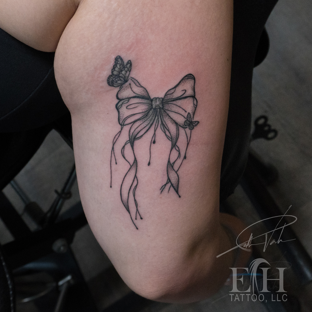Bow and butterflies realism tattoo on the forearm by Donald Voelker