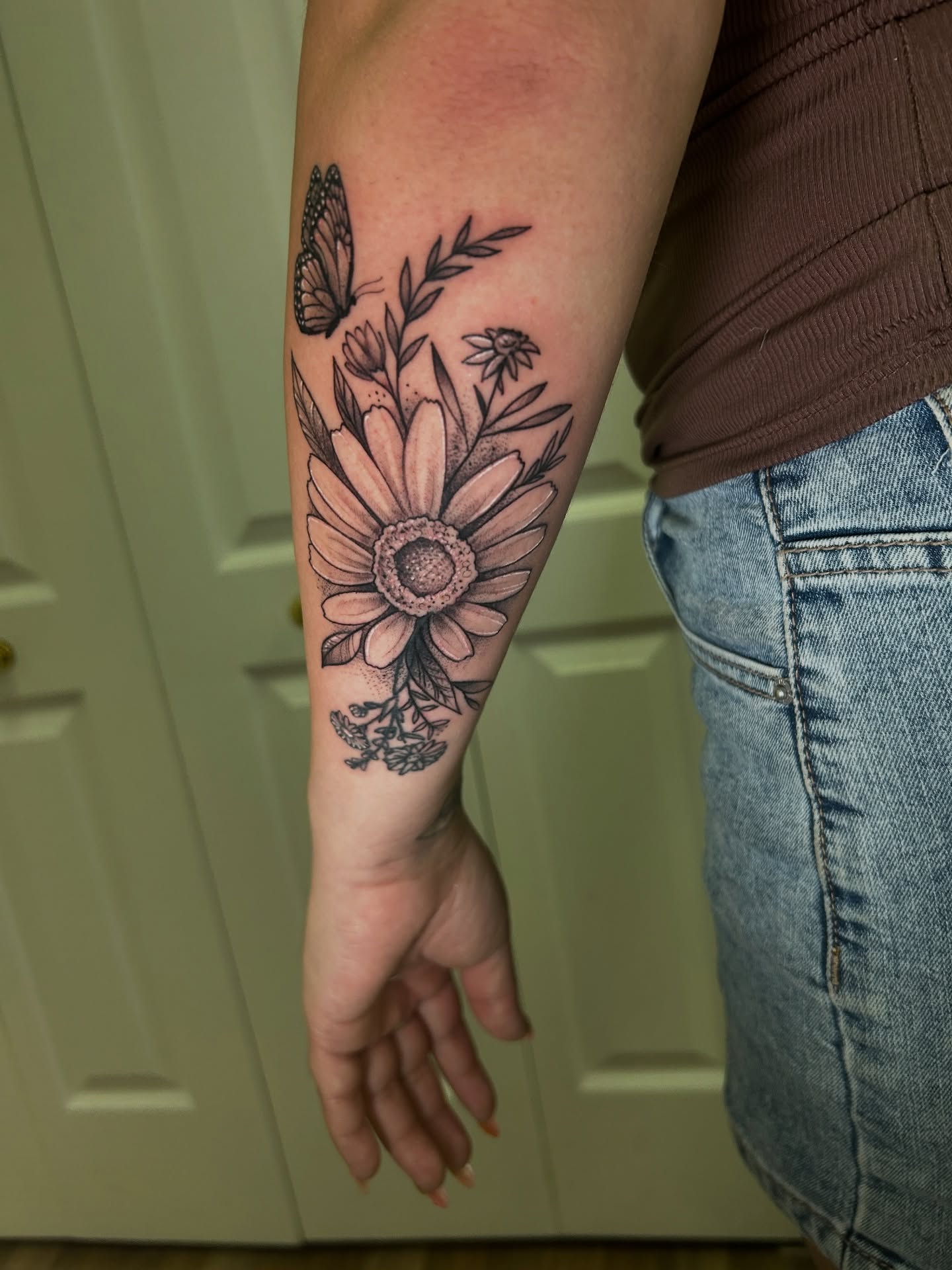 Sunflower and butterfly black and grey tattoo on the forearm by Mando Castro