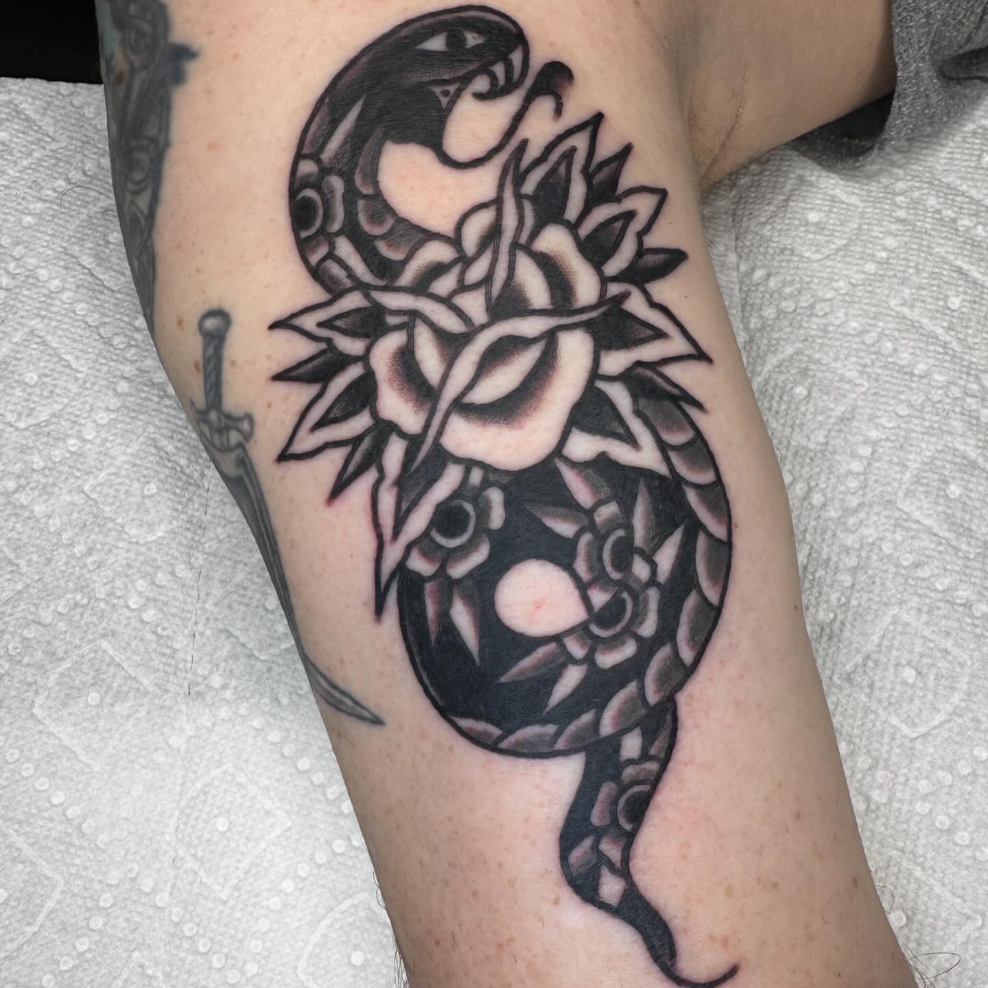 Snake and lotus black and grey tattoo on the forearm by JoJo Benton