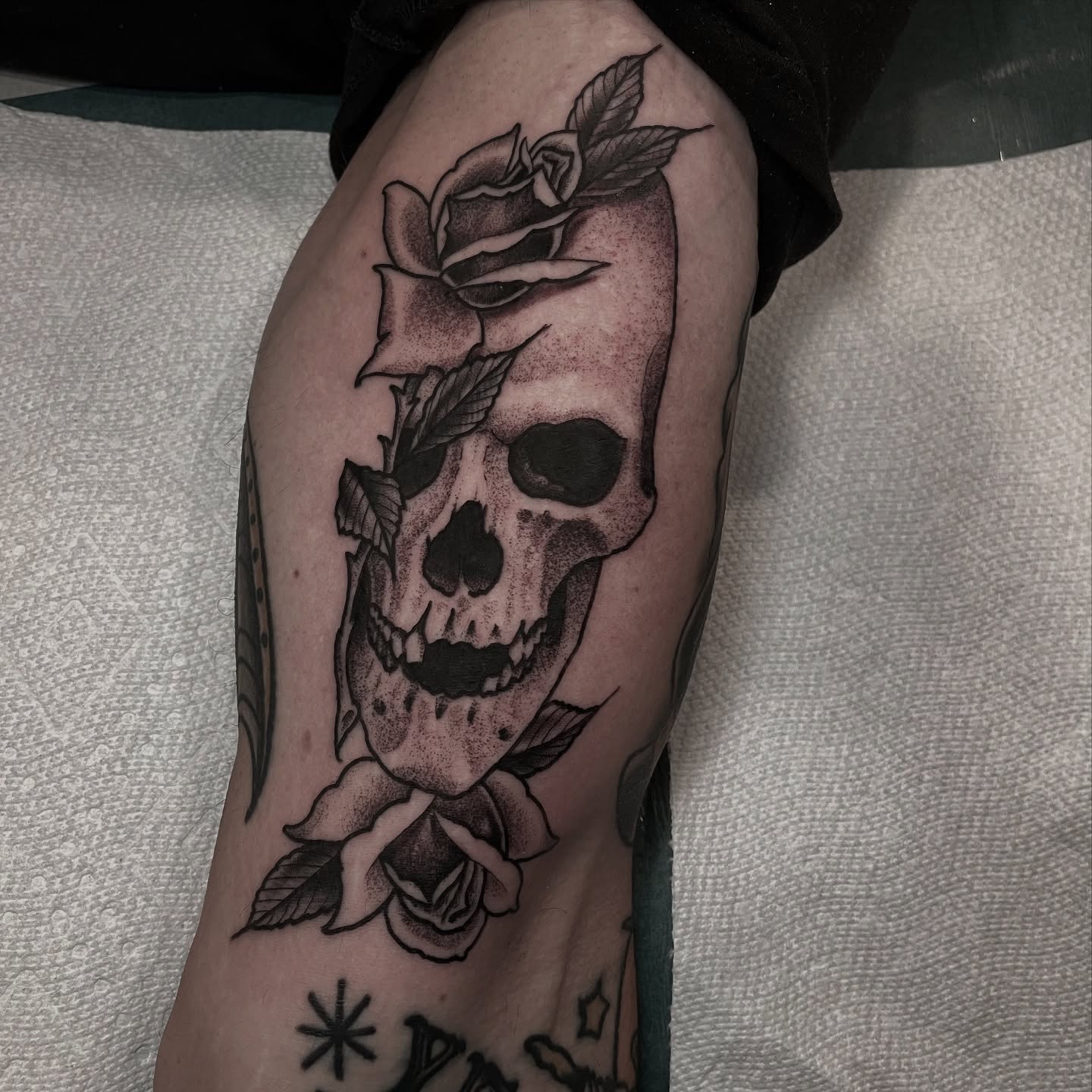 Skull and roses dotwork tattoo on the thigh by Ian Spong