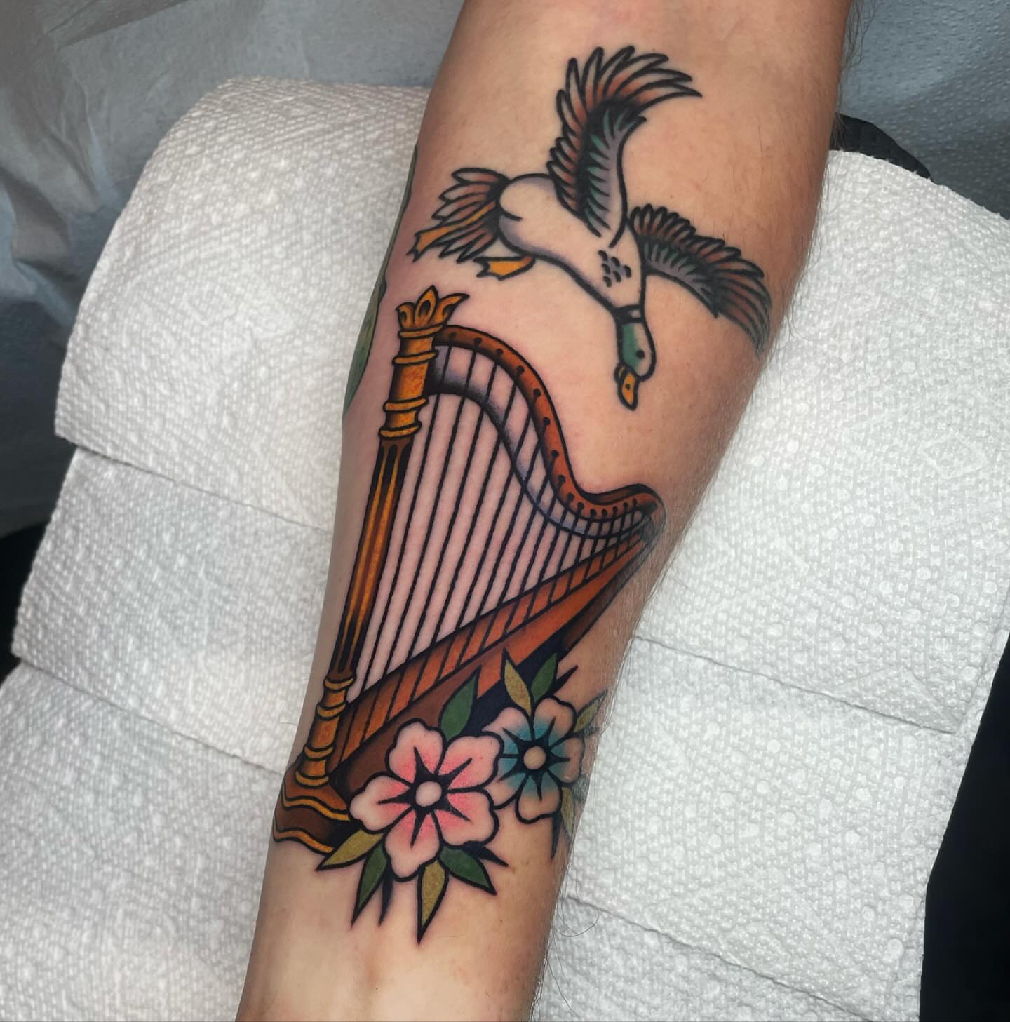 Harp and goose American traditional tattoo on the forearm by Nova Vaughn