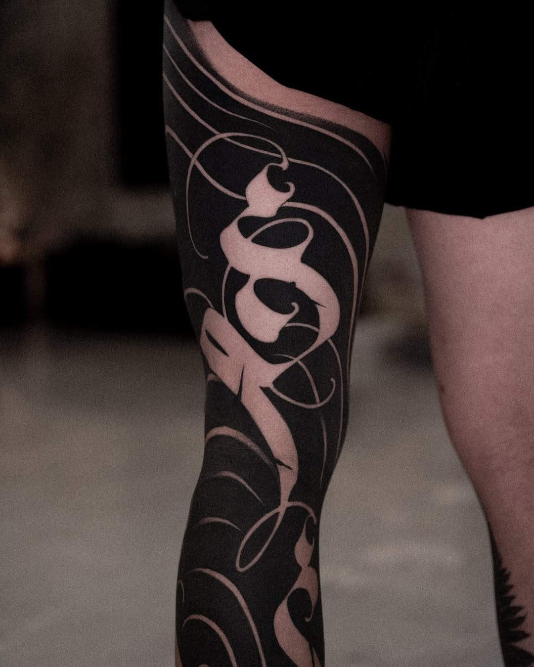 Ornamental script blackwork tattoo on the leg by Low, Brooklyn, New York