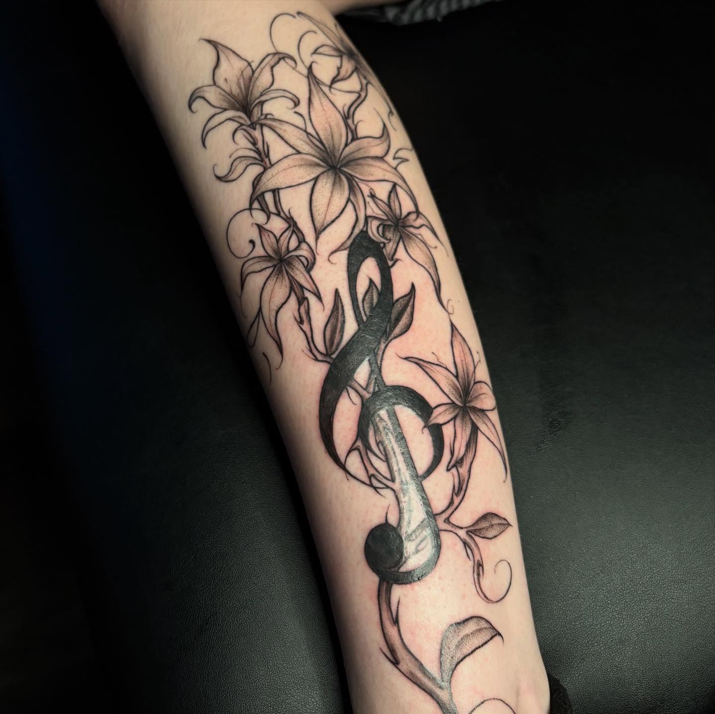 Music note and lilies realism tattoo on the forearm by amy mangeri ๐ฆ