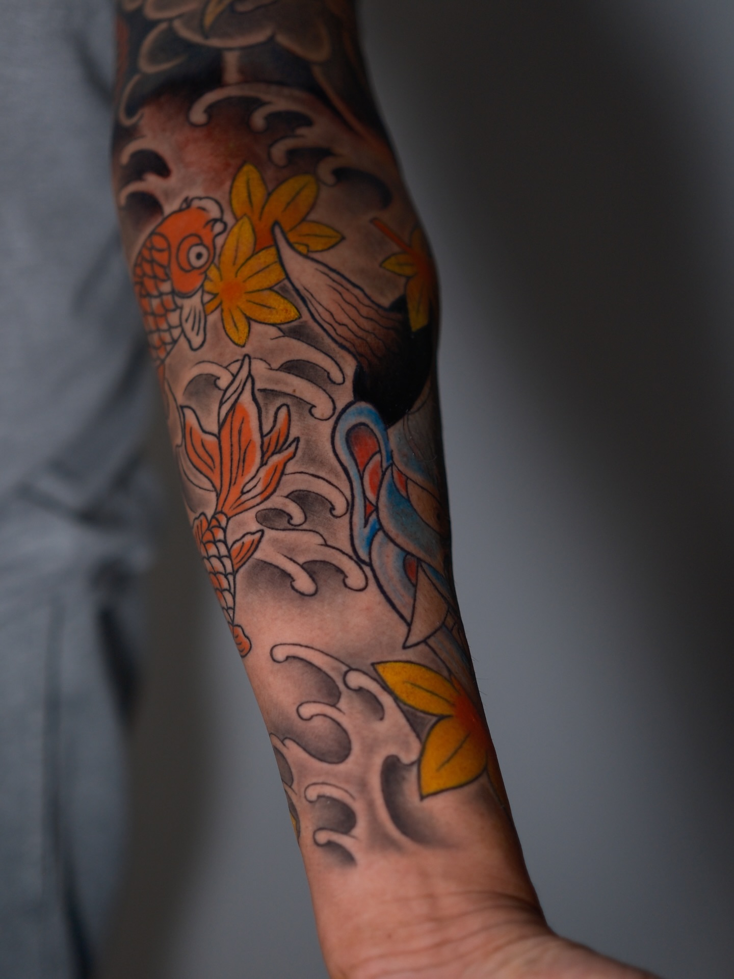 Koi fish and flowers American traditional tattoo on the forearm by Tattoo Artist Los Angeles