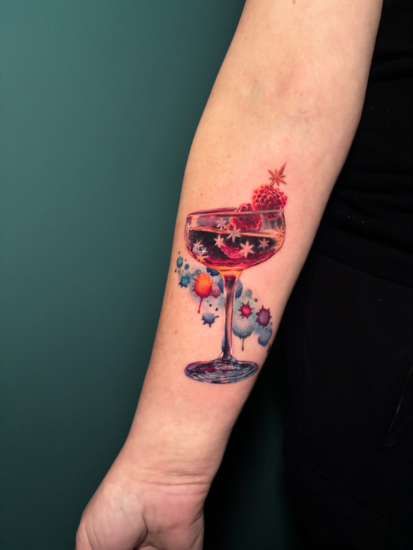 Martini glass with berries watercolor tattoo on the forearm by Meg Mayhem ๐จ Sarenity Tattoo