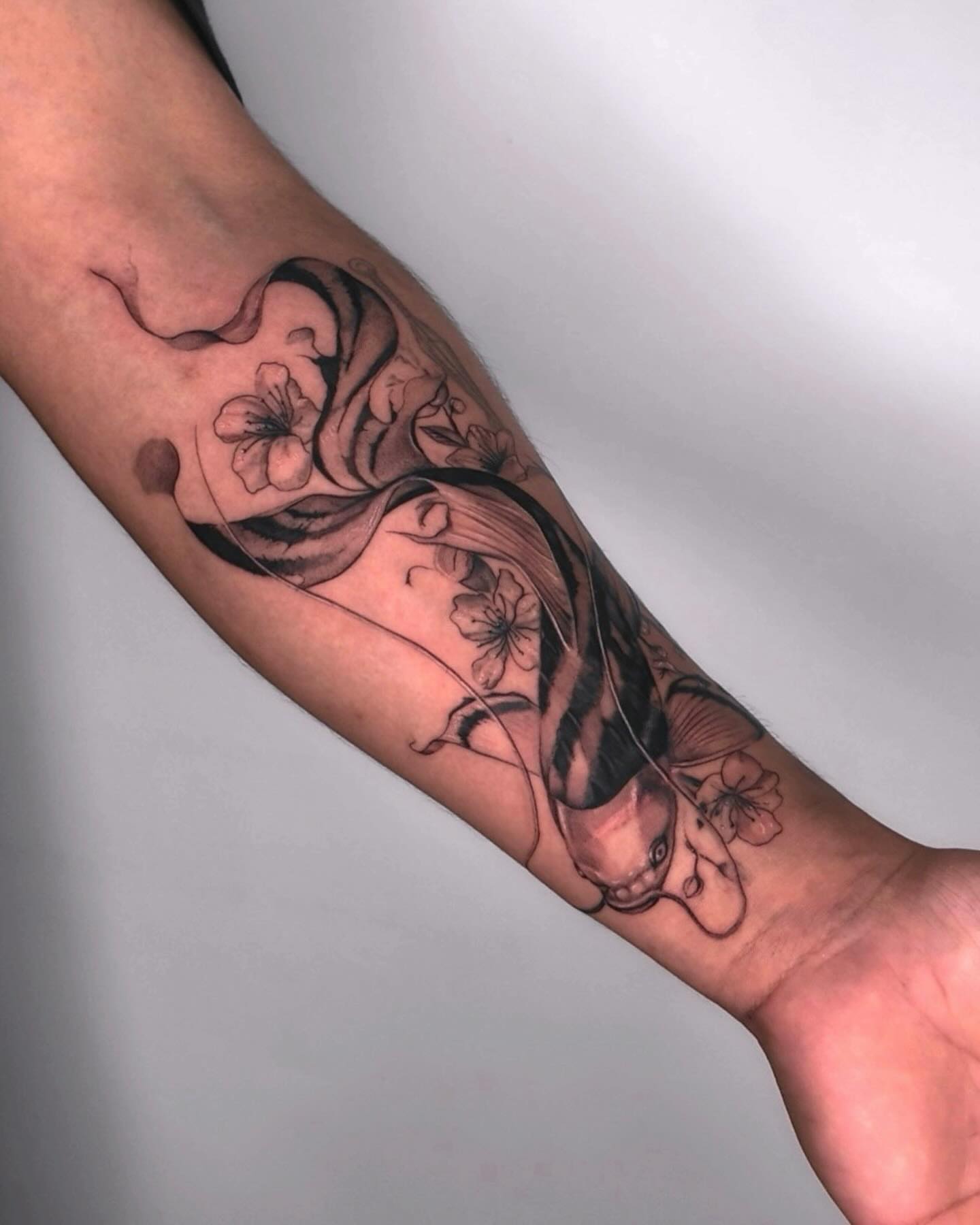 Koi fish and flowers realism tattoo on the forearm by Gabriel
