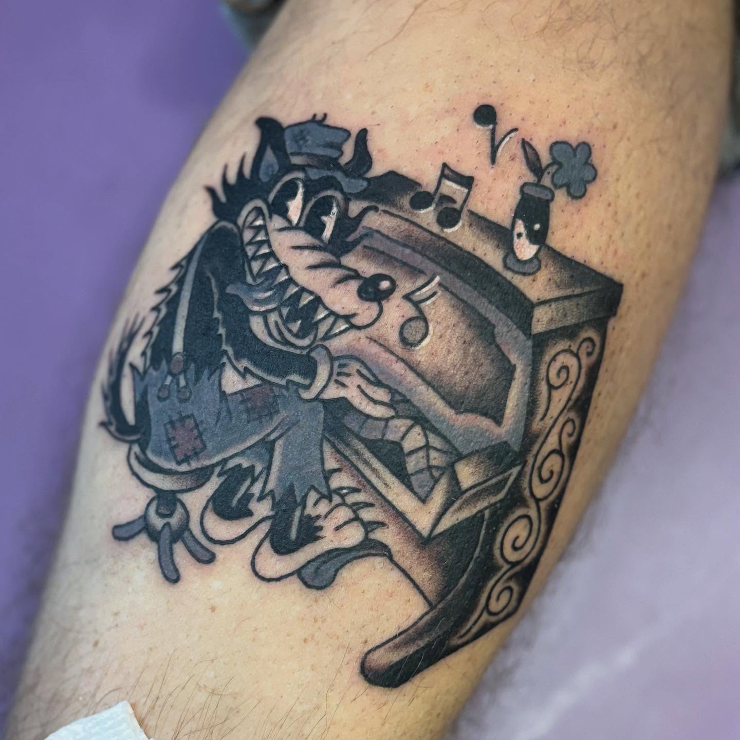 Wolf playing music black and grey tattoo on the forearm by Angie Isbell
