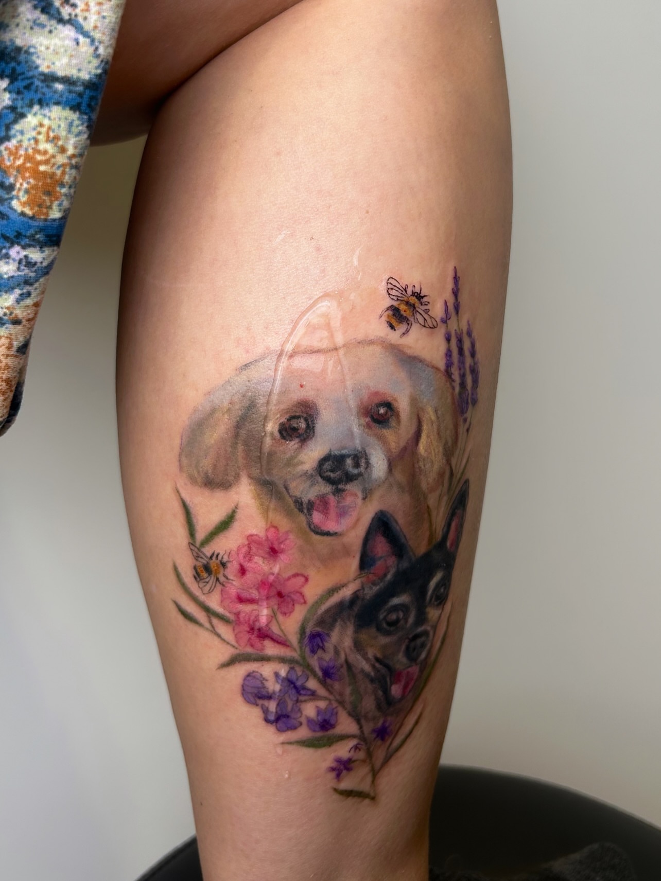Dogs and flowers watercolor tattoo on the thigh by Mackenzie