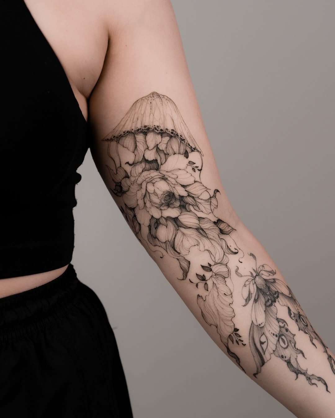 Jellyfish and floral design with moths fine line tattoo on the forearm by Marek