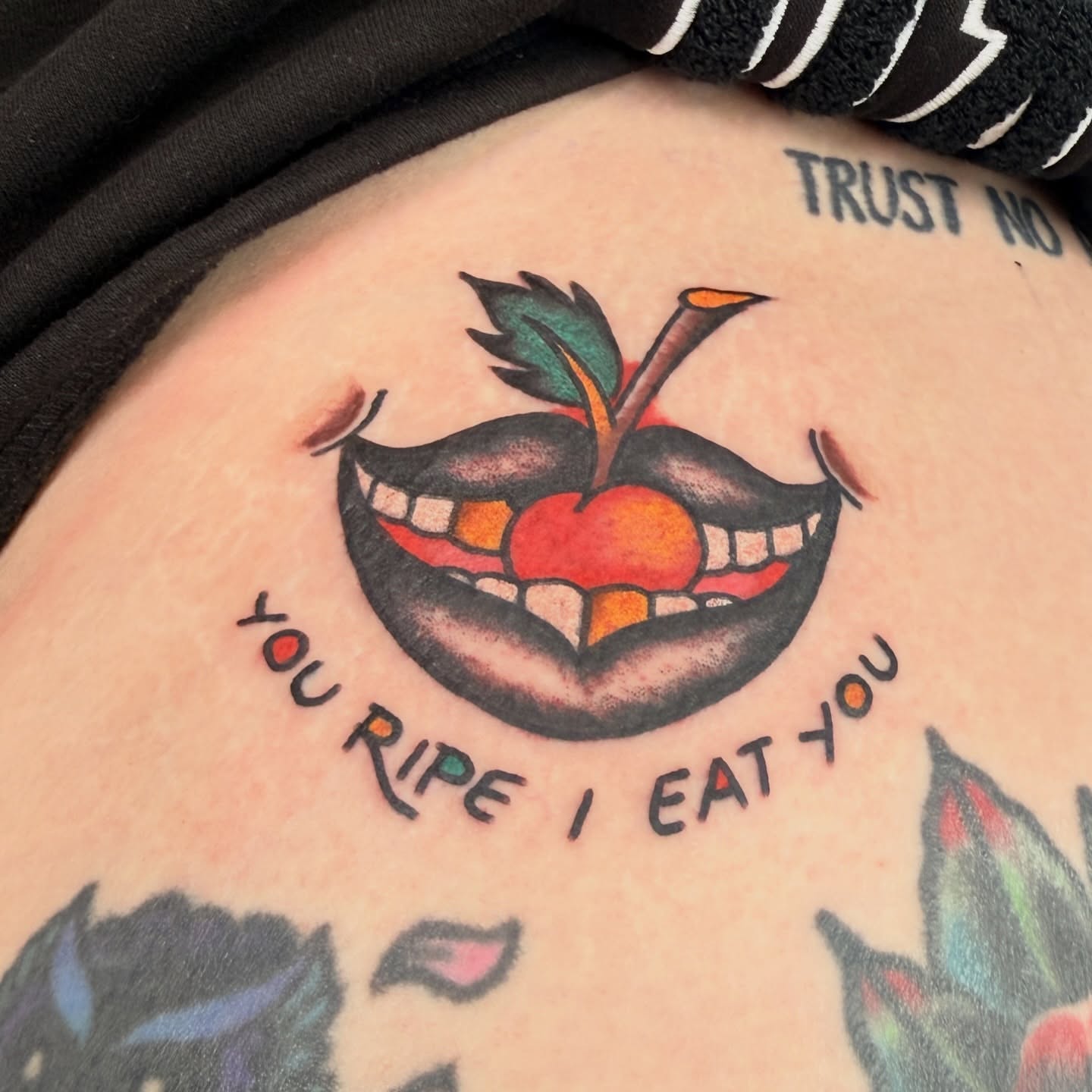 Smiling apple with teeth American traditional tattoo on the thigh by Stevie Lowenstein, Cincinnati, Ohio