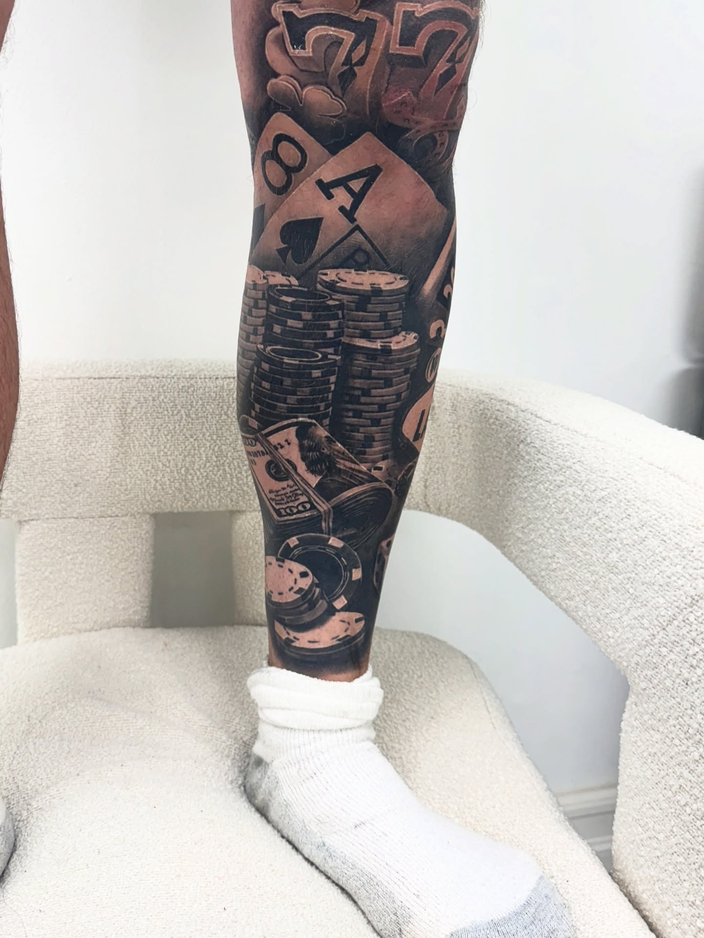 Cards and poker chips black and grey tattoo on the leg by Anthony Duran