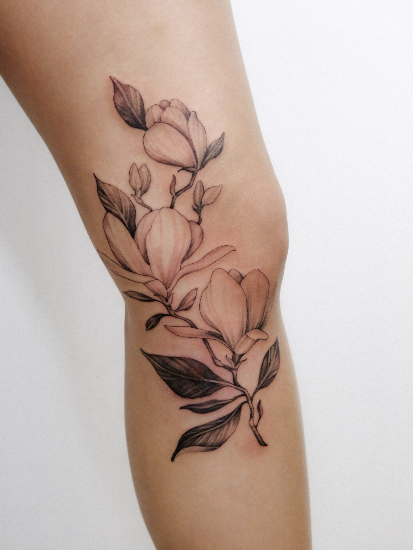 Magnolia flowers black and grey tattoo on the forearm by Alena Zozulenko