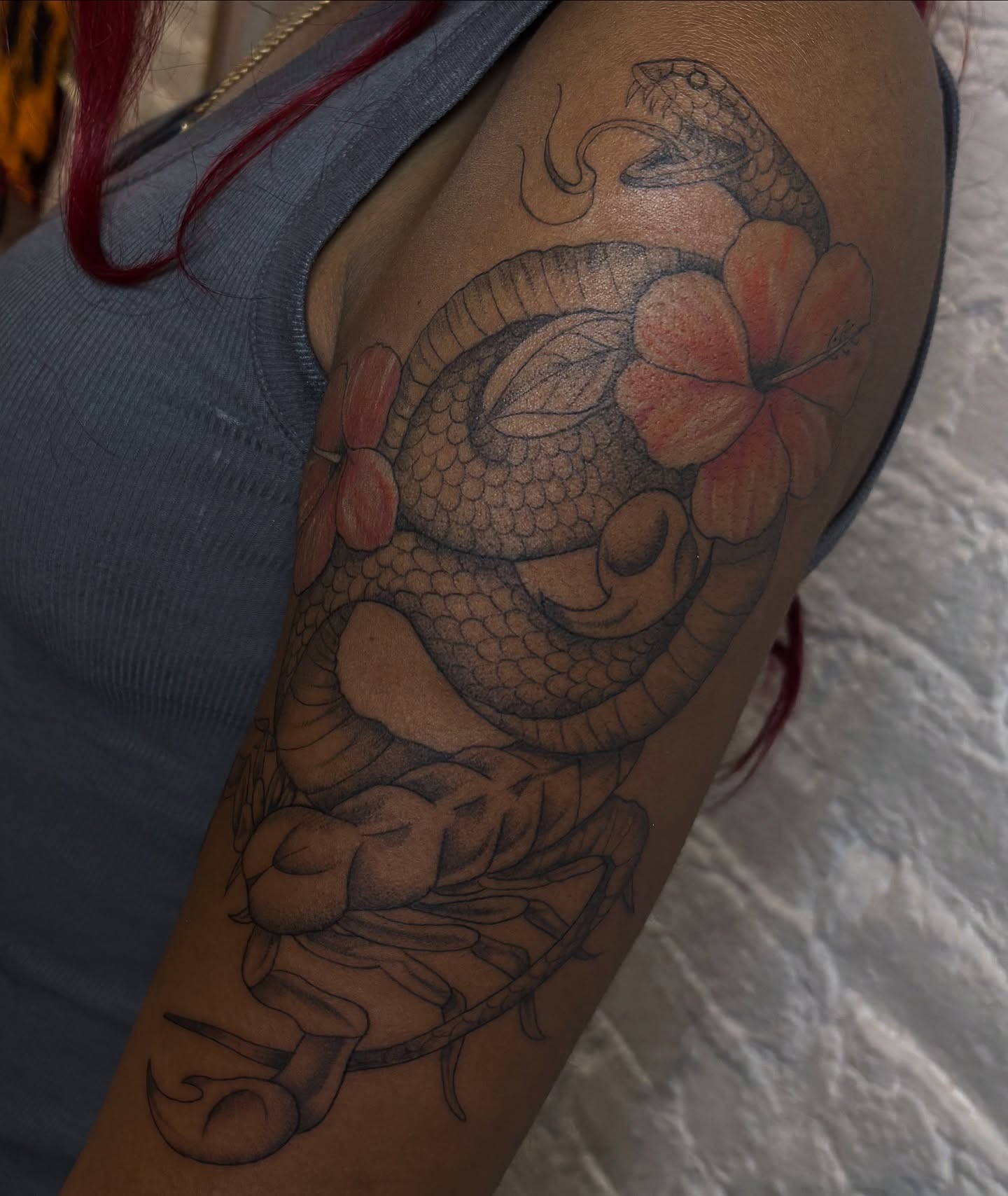 Snake and flower black and grey tattoo on the upper arm by Sydney Gallucci