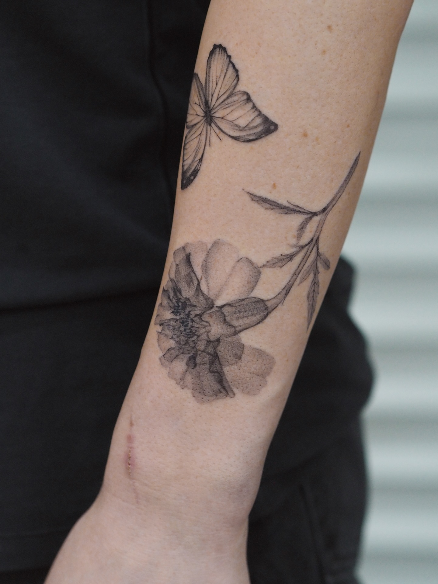 Flower and butterfly black and grey tattoo on the forearm by Anastasiia Pakhanova ♥ tattoo artist