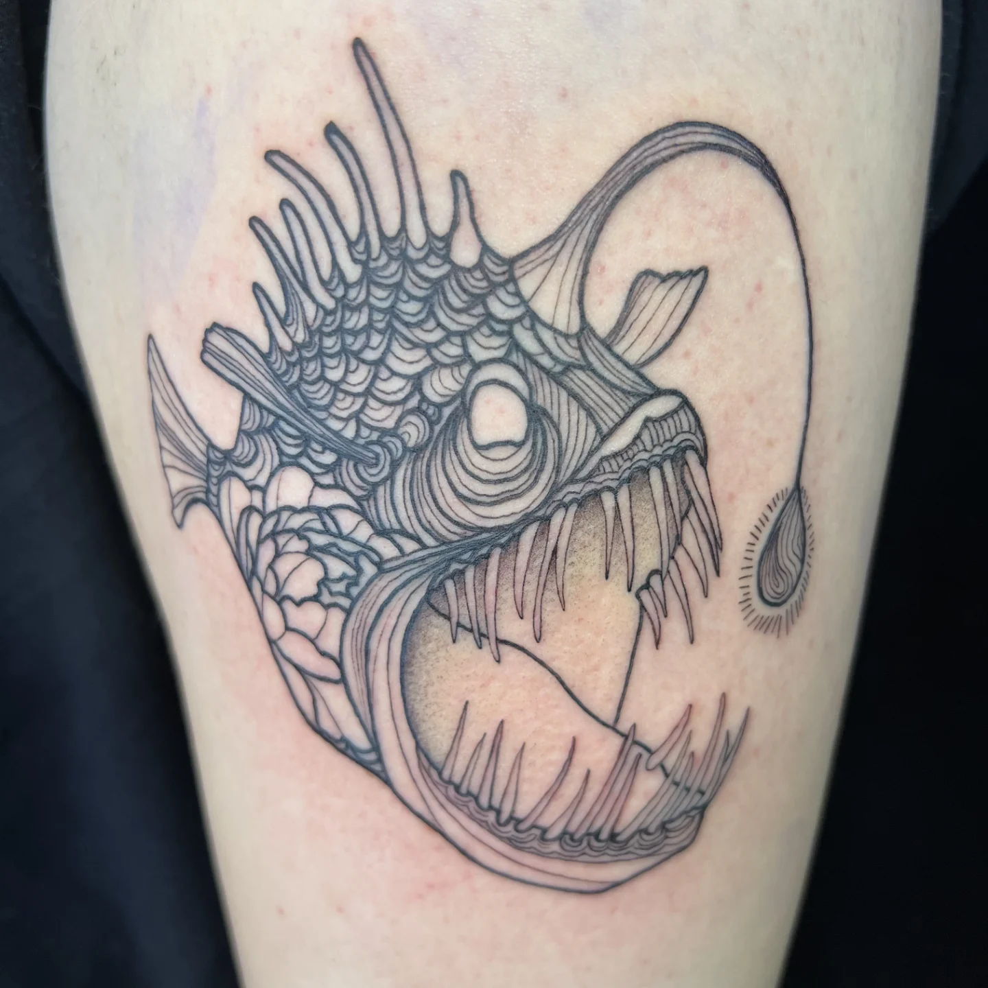 Angler fish black and grey tattoo on the thigh by Lora Bird