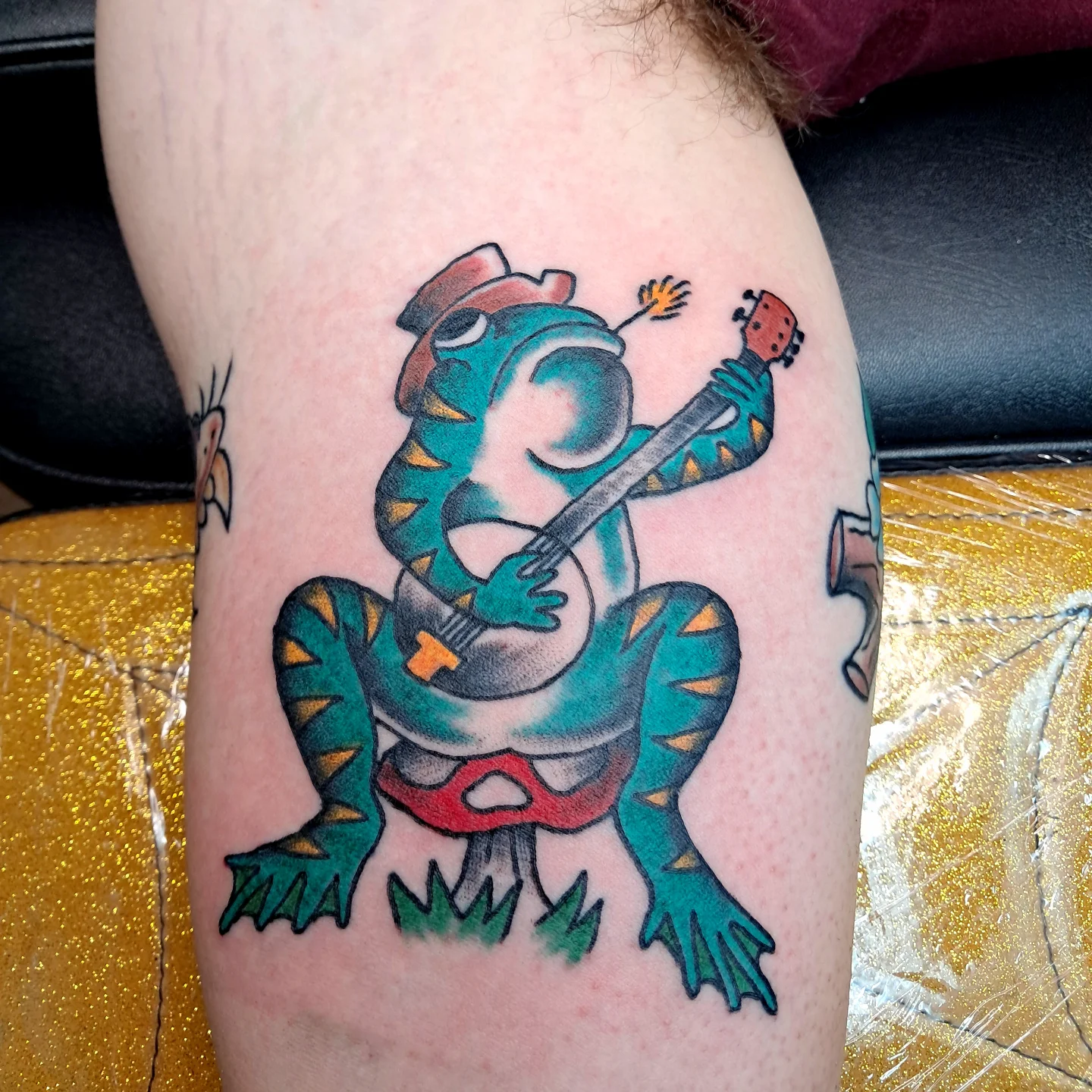 Lizard playing guitar American traditional tattoo on the thigh by Reb Fularz