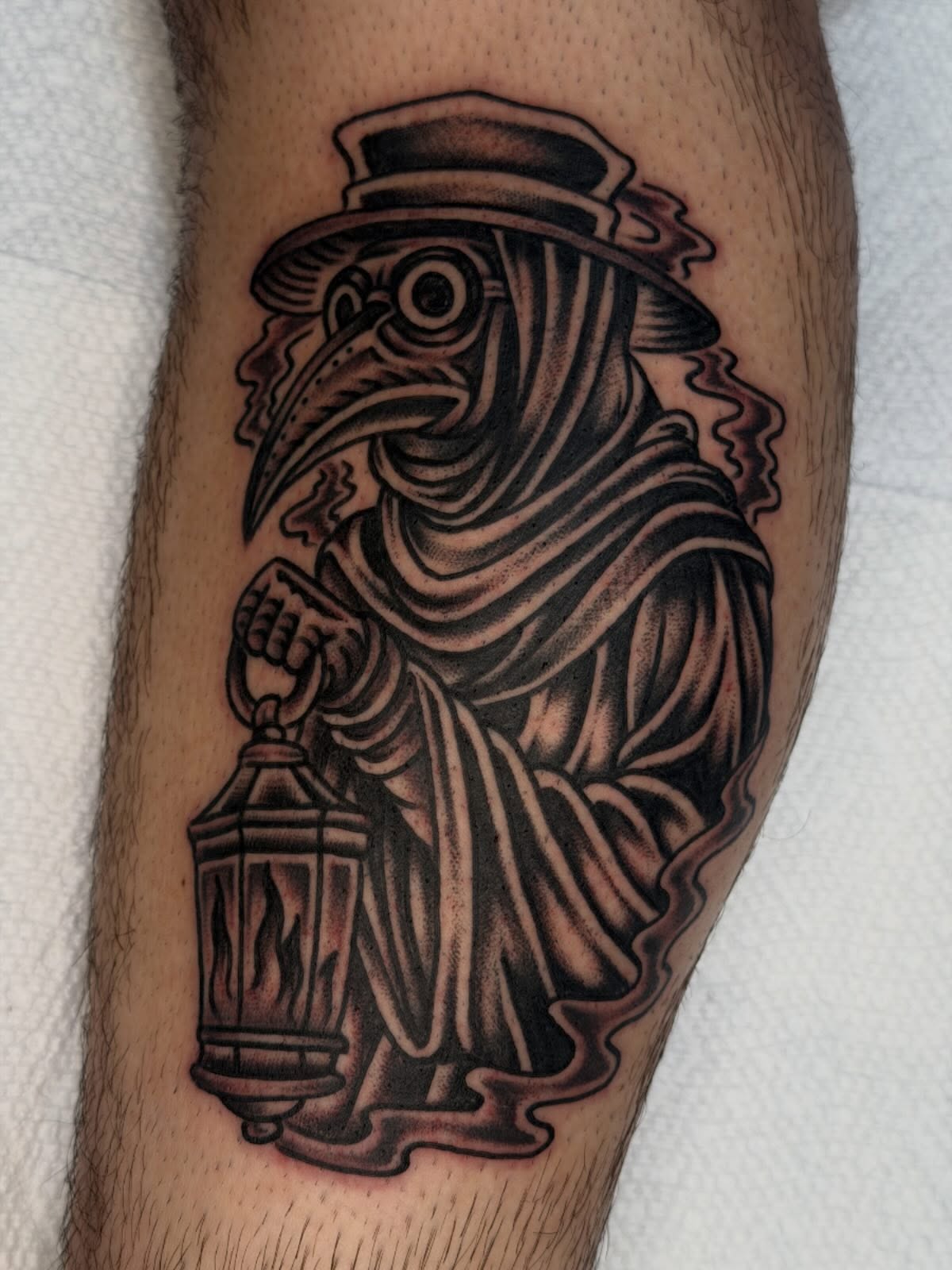 Plague doctor black and grey tattoo on the forearm by Tony Kaplan