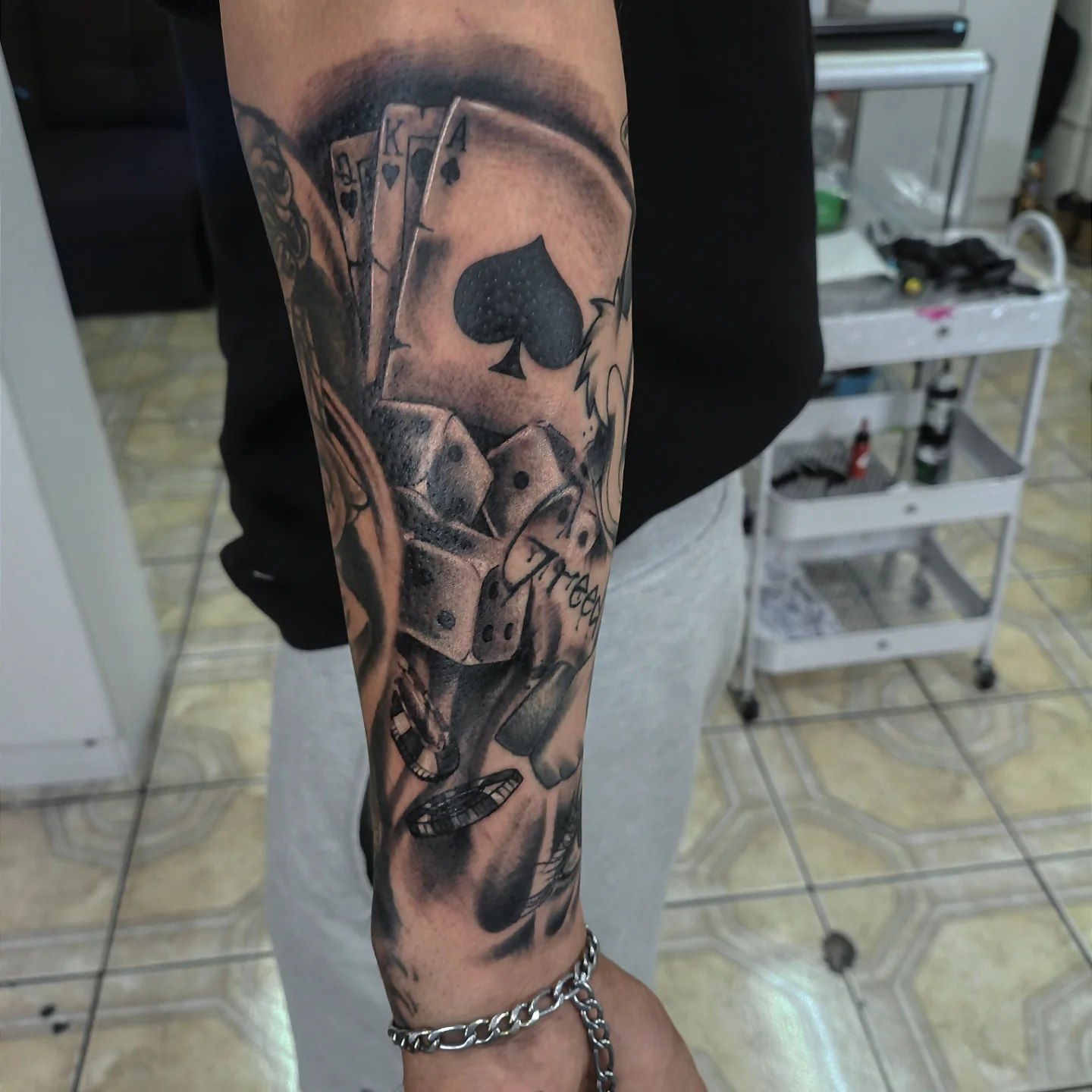Playing cards black and grey tattoo on the forearm by Alexander Tattooink