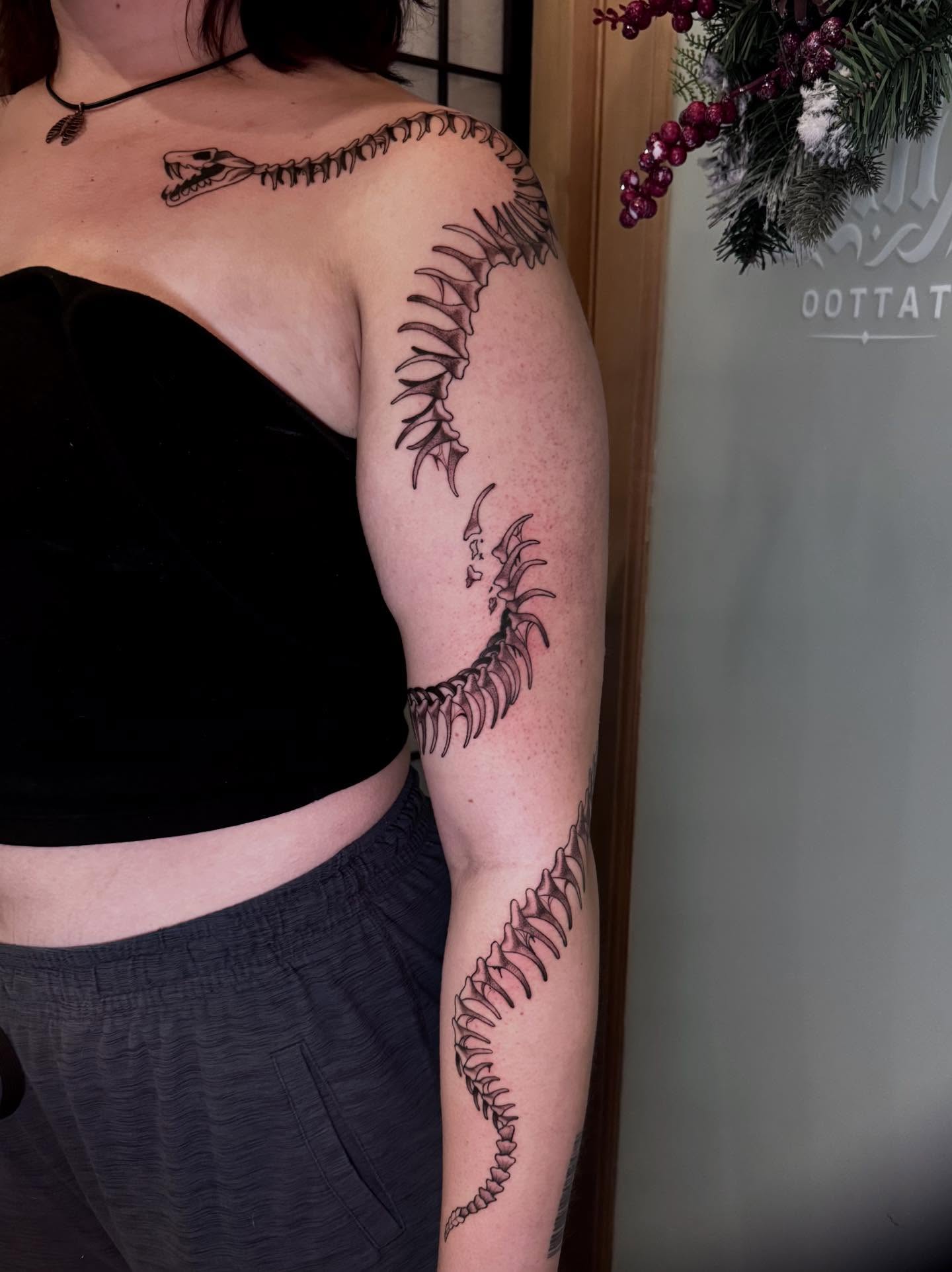 Spine black and grey tattoo on the upper arm by Morgan Peeples