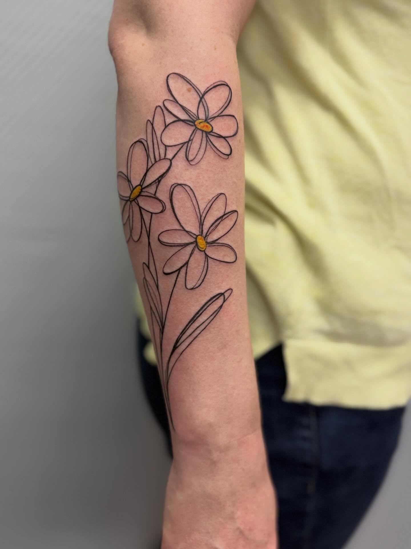 Daisies fine line tattoo on the forearm by Die Ivo, Bielefeld, Germany