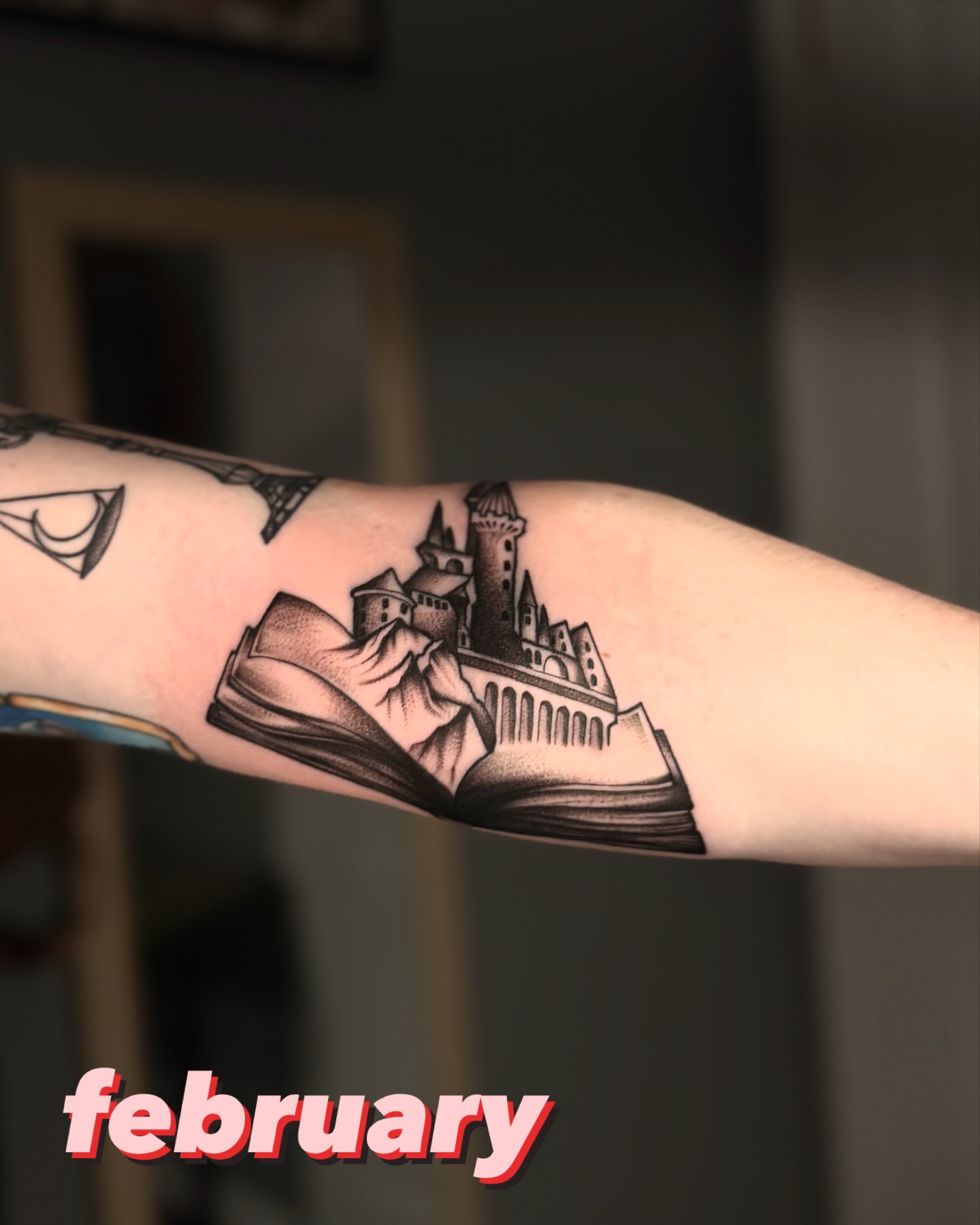 Castle on book black and grey tattoo on the forearm by laura baldwin