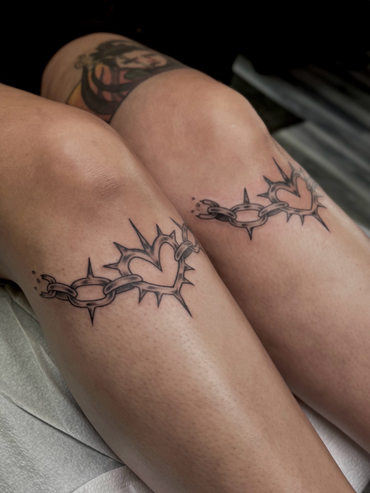 Heart with thorns and chains black and grey tattoo on the thigh by Ally Ghastly, Eugene, Oregon