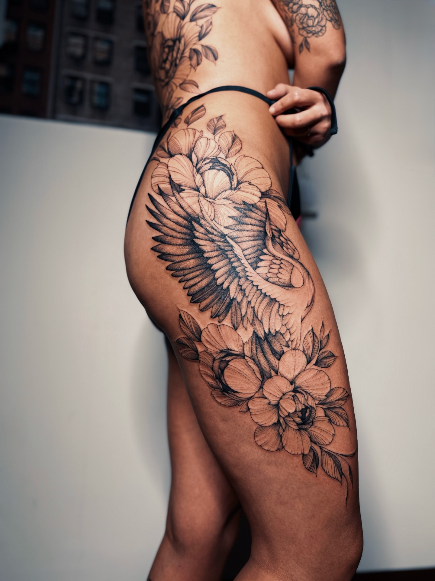 Peony and swan black and grey tattoo on the thigh by Olha Tytarenko