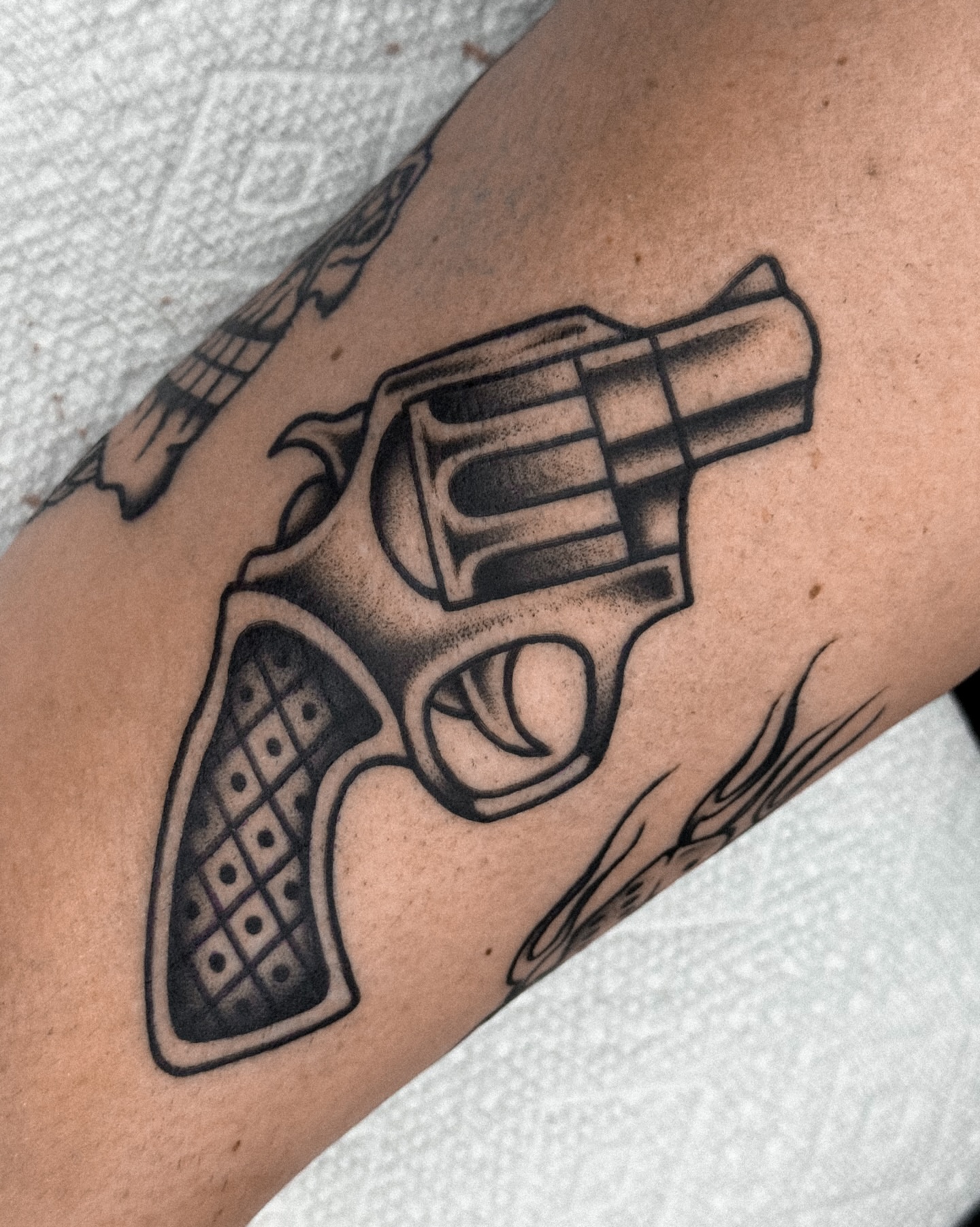 Revolver black and grey tattoo on the forearm by Samuel Dickey