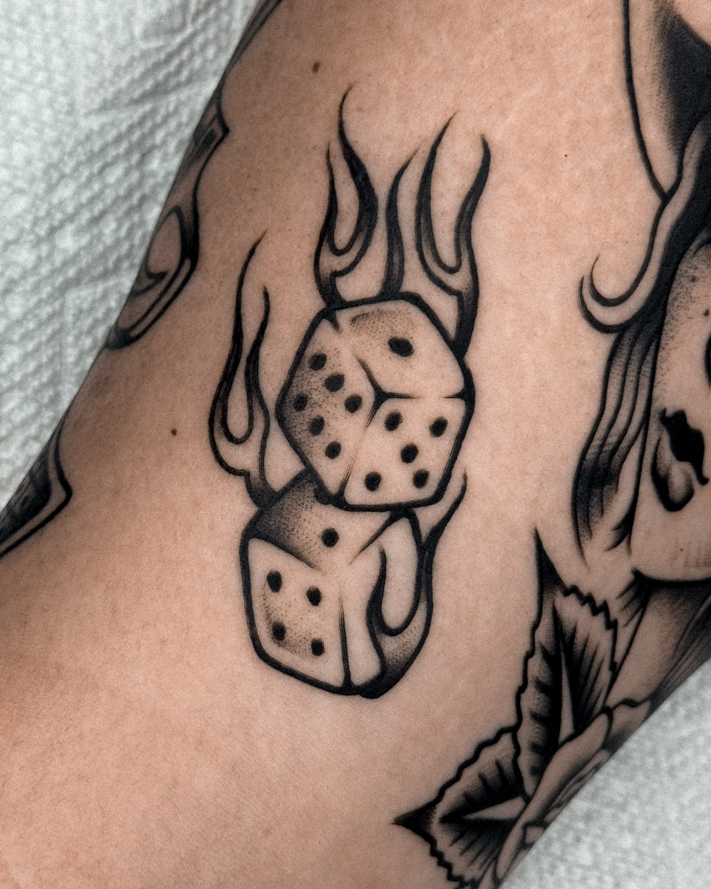 Flaming dice black and grey tattoo on the forearm by Samuel Dickey