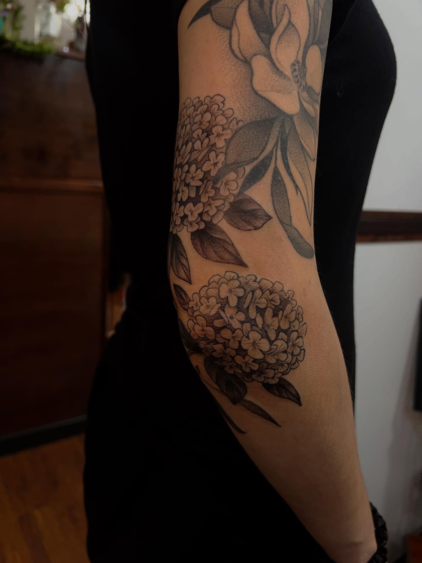 Flowers black and grey tattoo on the forearm by Avrey Simone