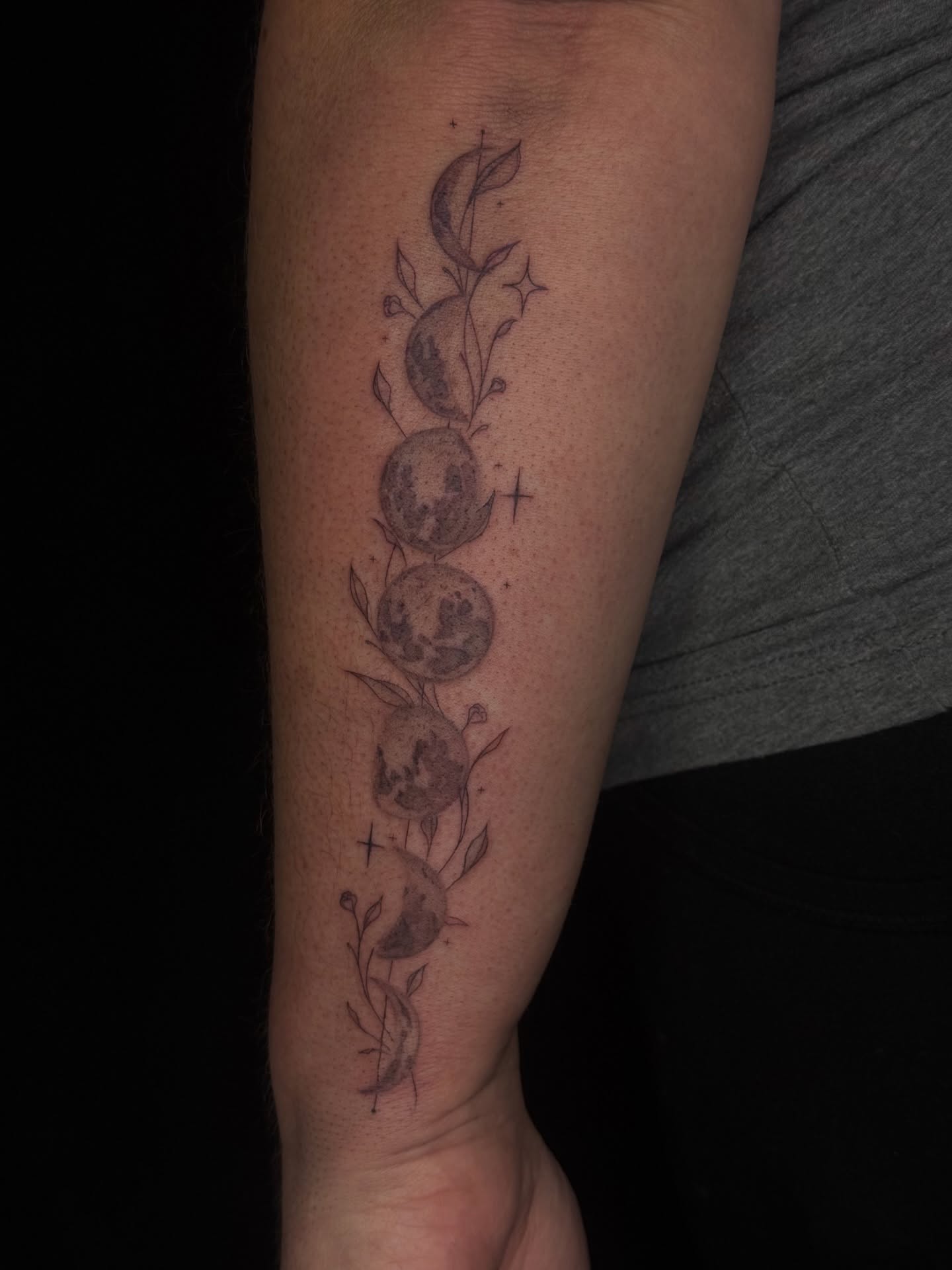 Phases of the moon black and grey tattoo on the forearm by elena