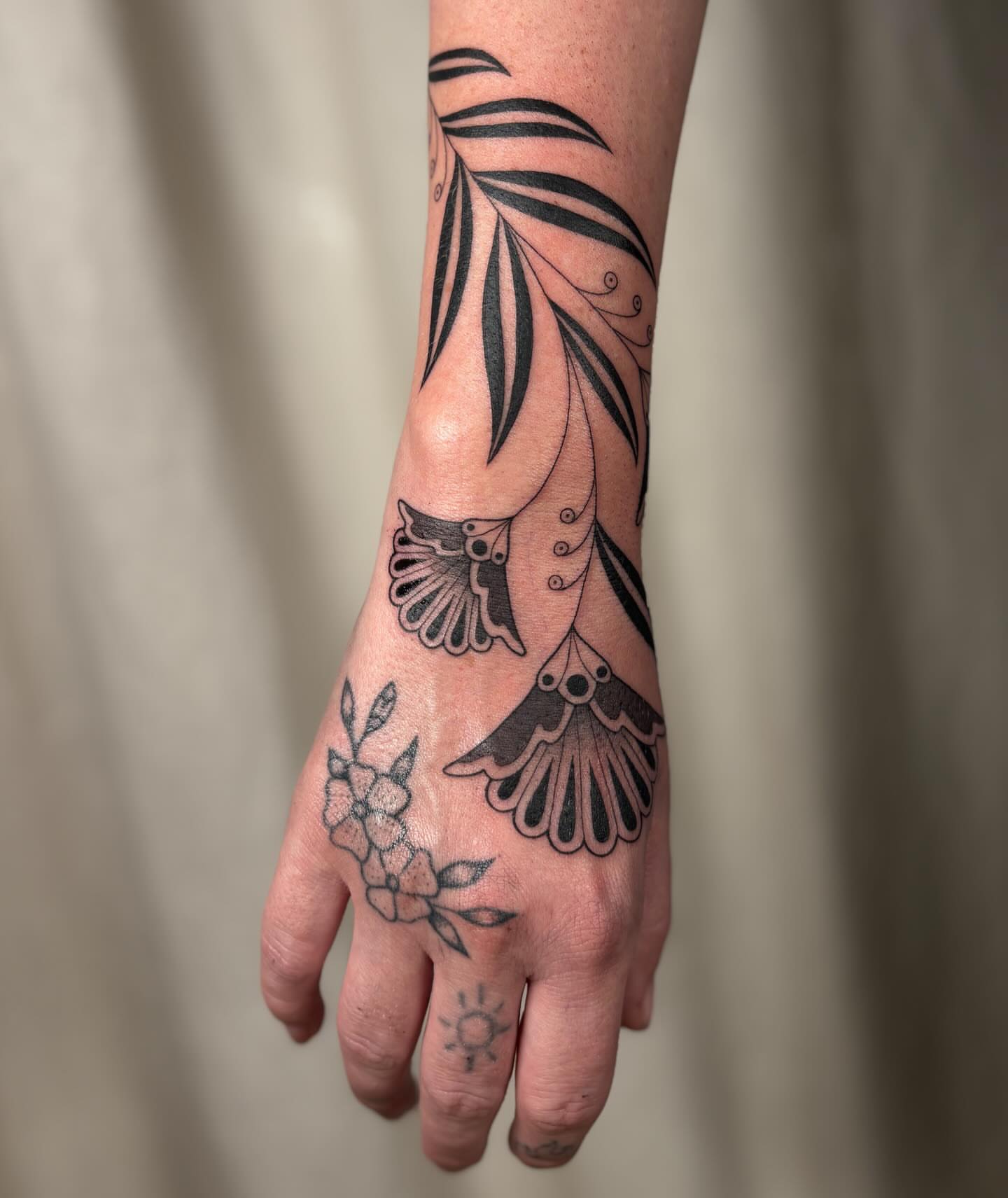 Bird and floral black and grey tattoo on the hand by Anna Sage