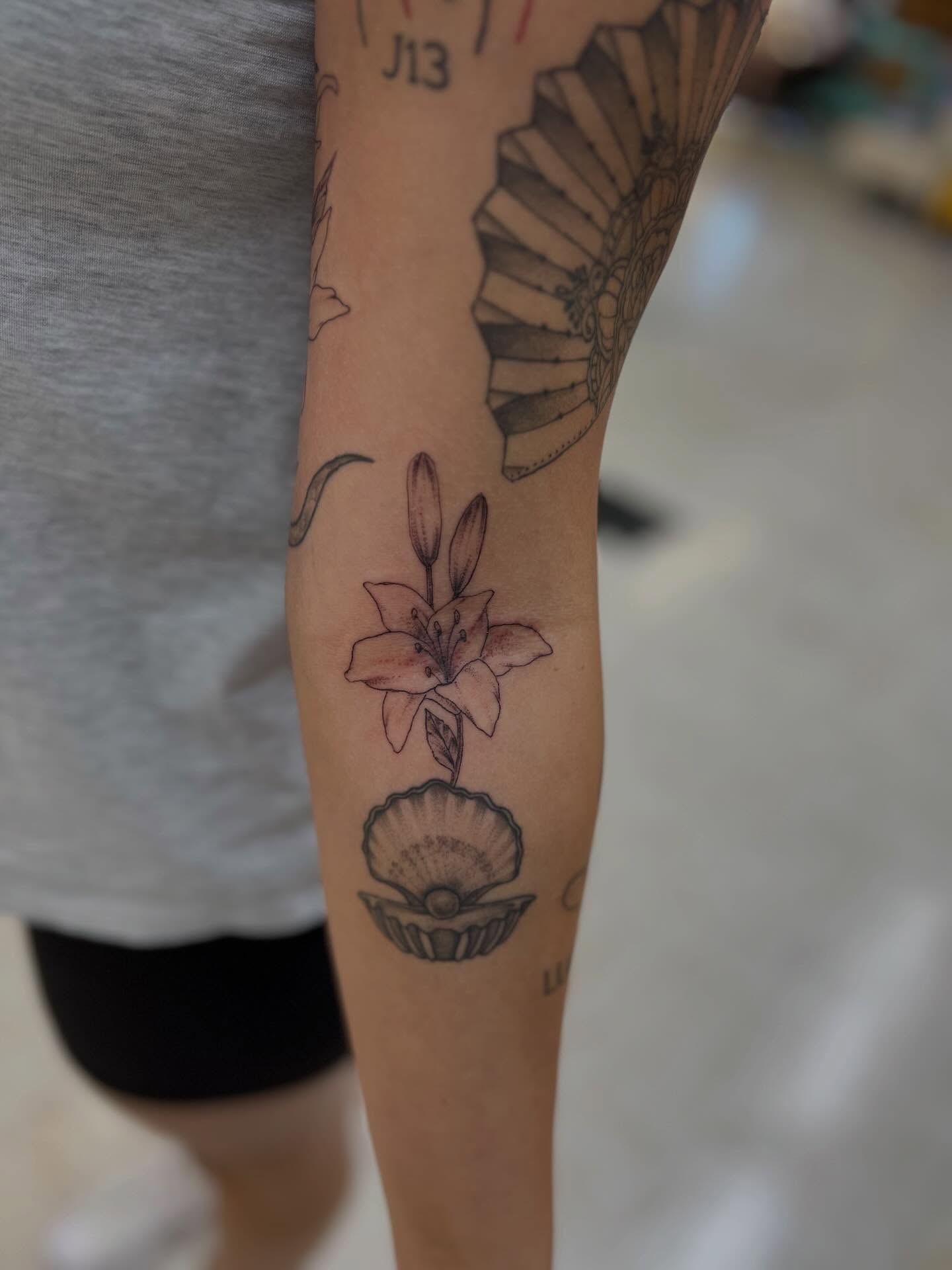 Lily in shell black and grey tattoo on the forearm by Levi Sawdon, Everett, Washington