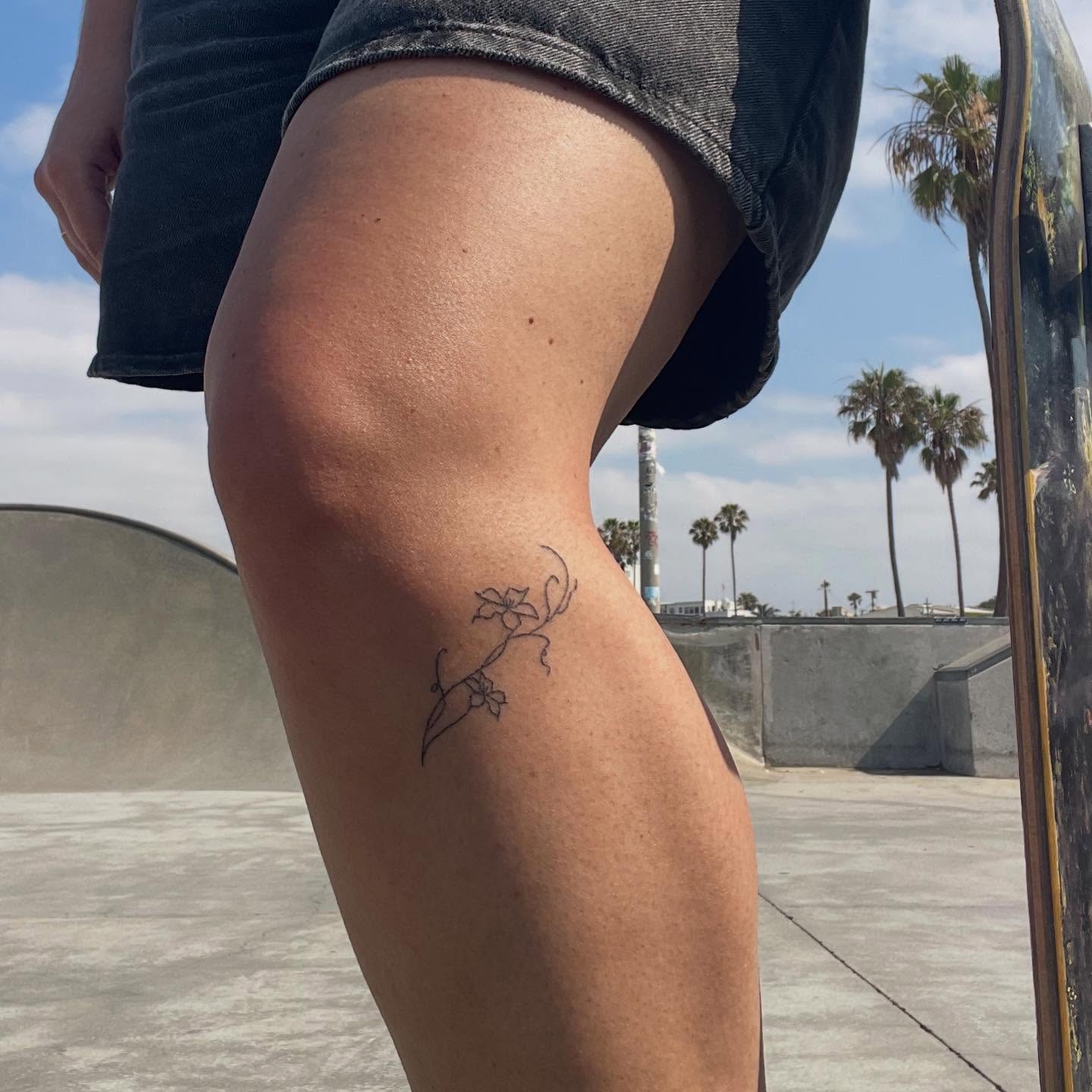 Flower vine fine line tattoo on the thigh by Alyssa