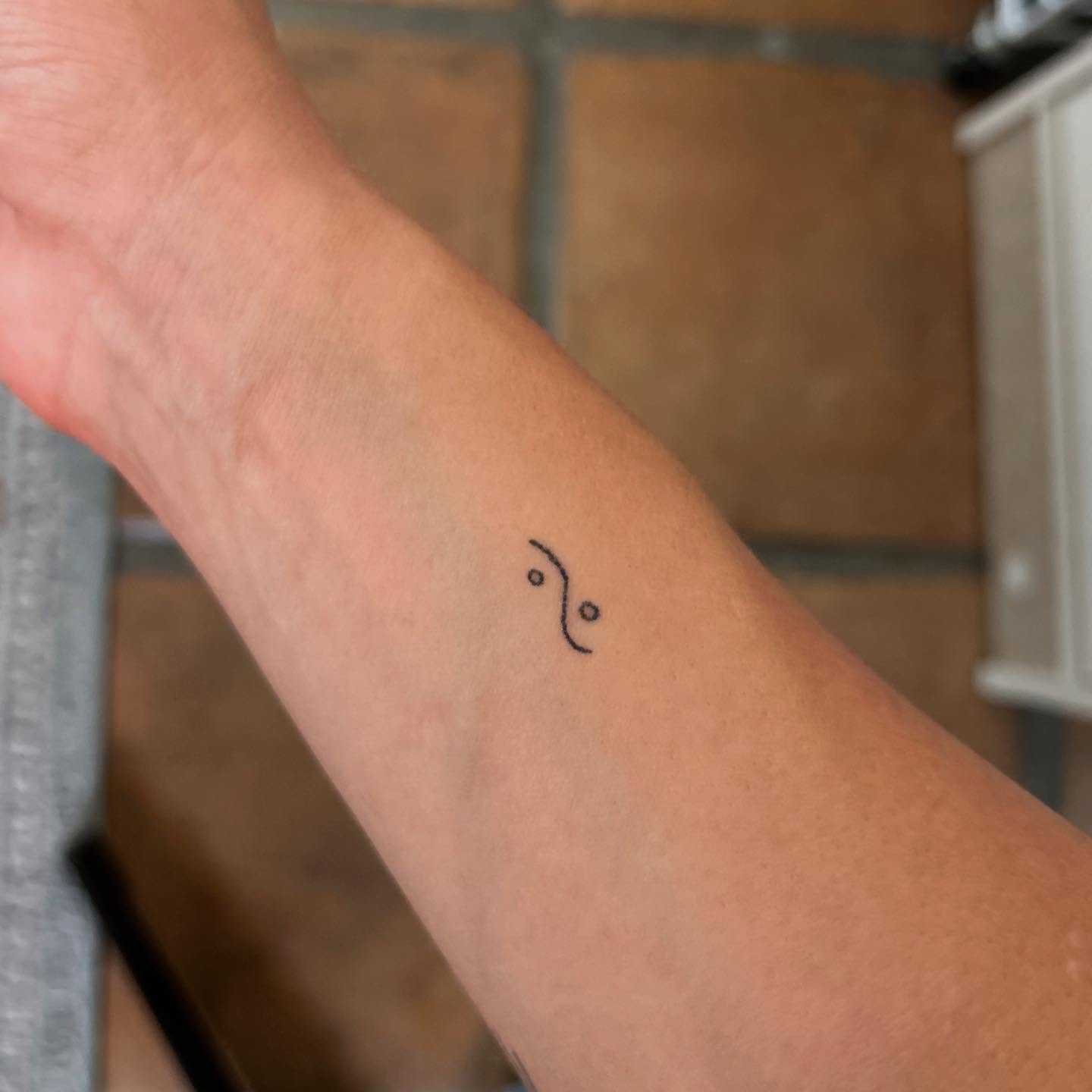 Zodiac symbol minimalist tattoo on the forearm by Alyssa