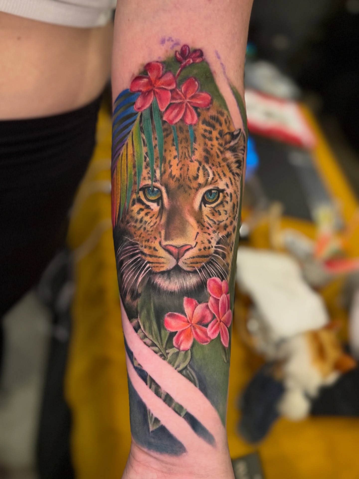 Leopard with flowers realism tattoo on the forearm by Kelsey Kemp