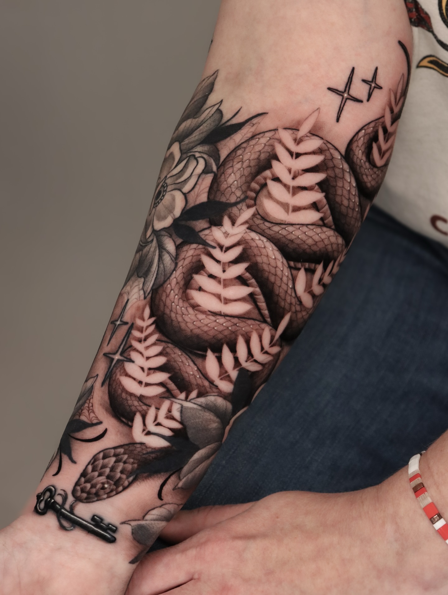 Snake and leaves realism tattoo on the forearm by Jeff Reindel